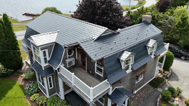 A colonial style home with a grey metal roof and white trim