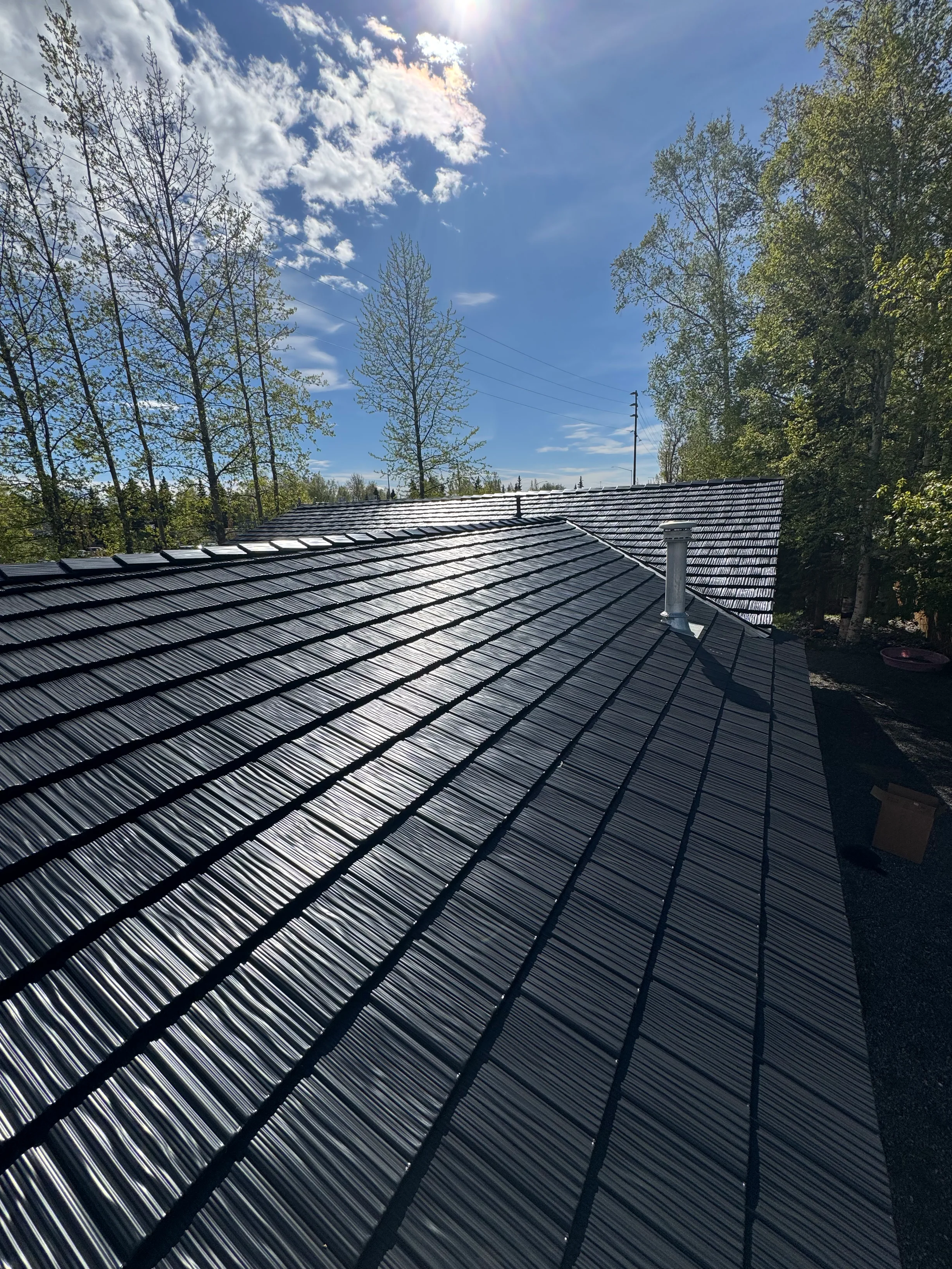 A modern metal roof on a single-family home in an urban or suburban setting, possibly with a blue sky or overcast conditions.