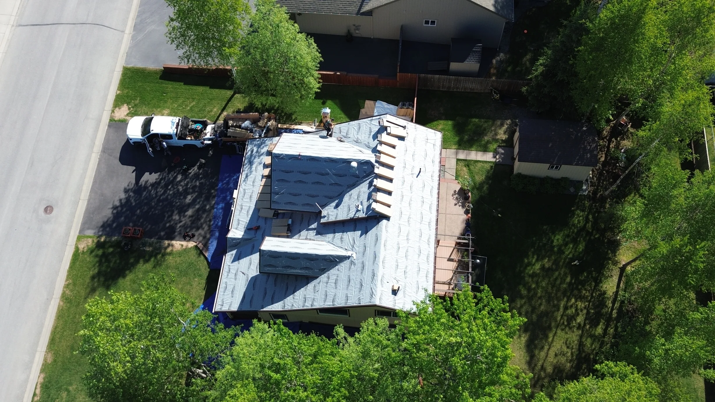 Aerial view of a modern, single-family home with a metal roof and lush greenery.