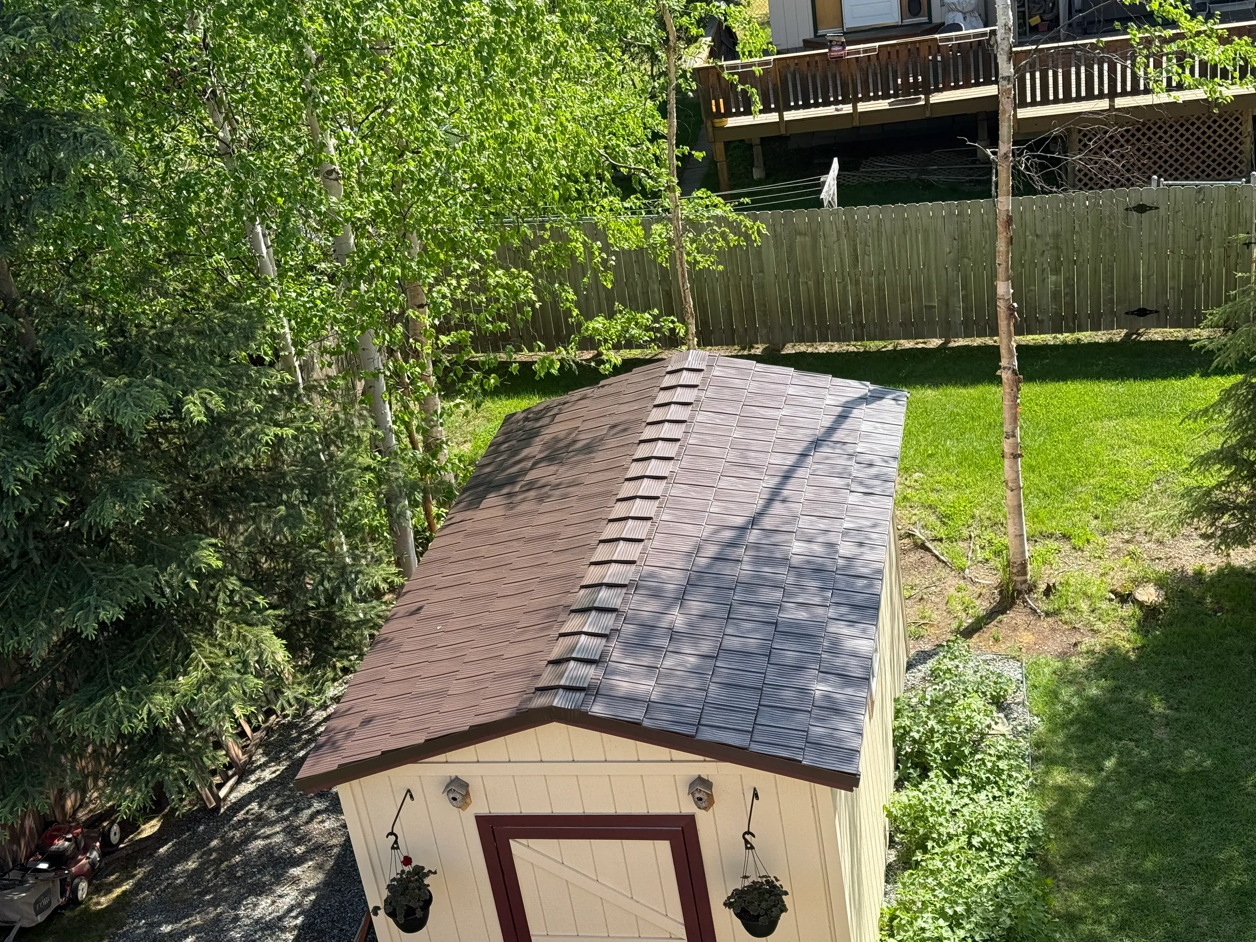 A modern house with a brown metal roof in a lush green urban setting.