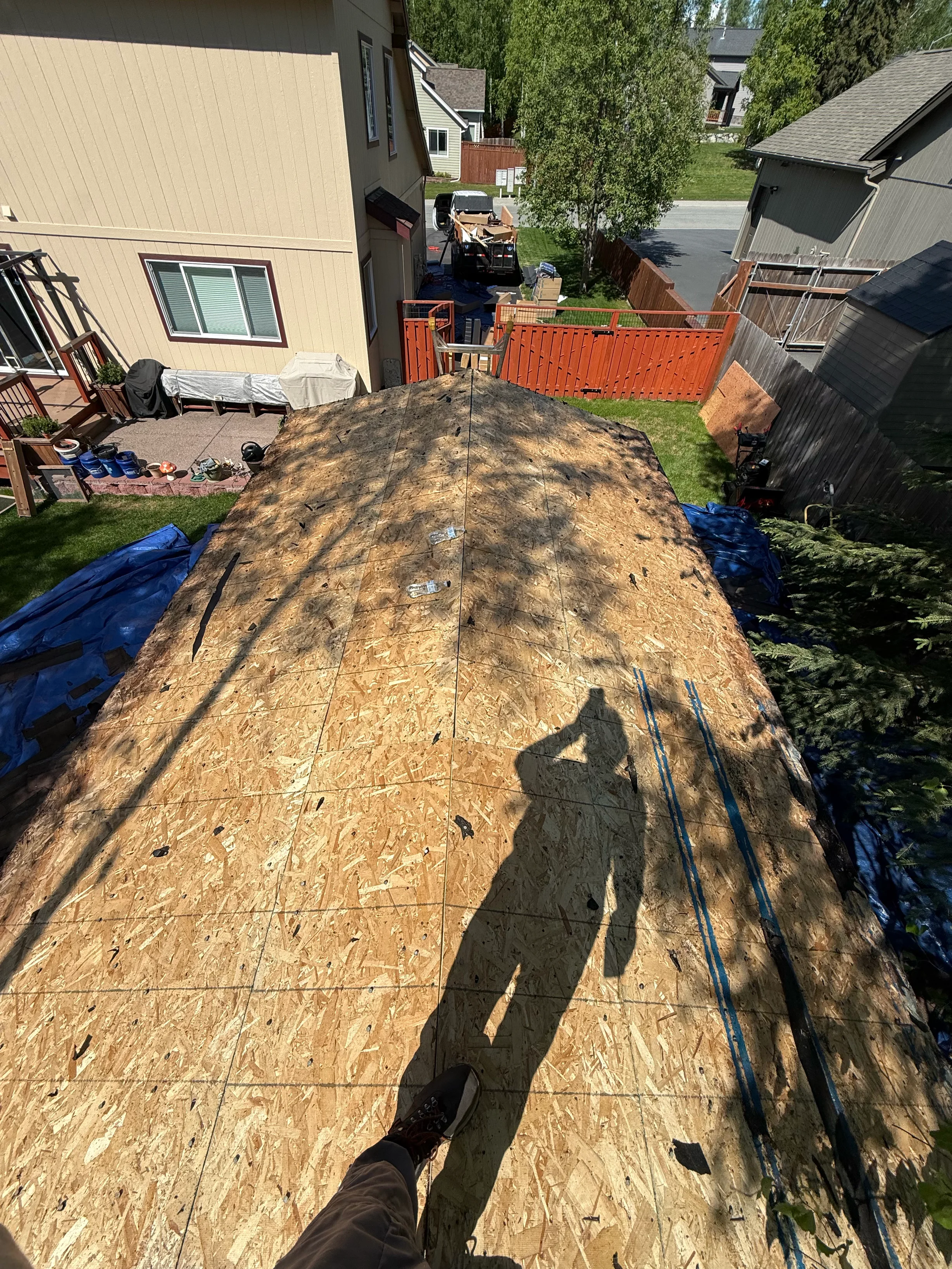 A new metal roof is being installed on a modern single-family home in a suburban area with lush greenery.