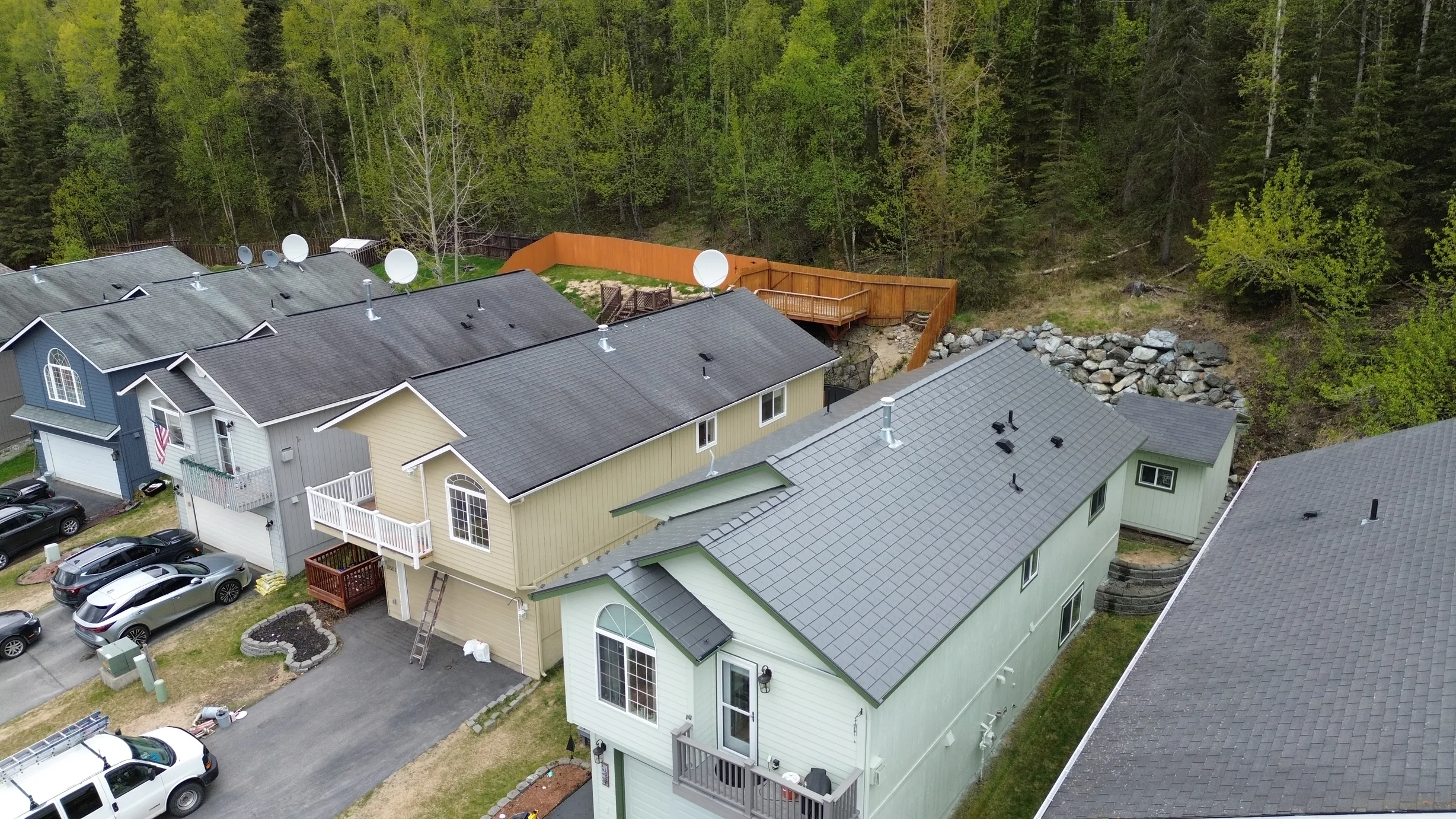 Aerial view of a large, two-story home with a grey metal roof and a light green exterior.