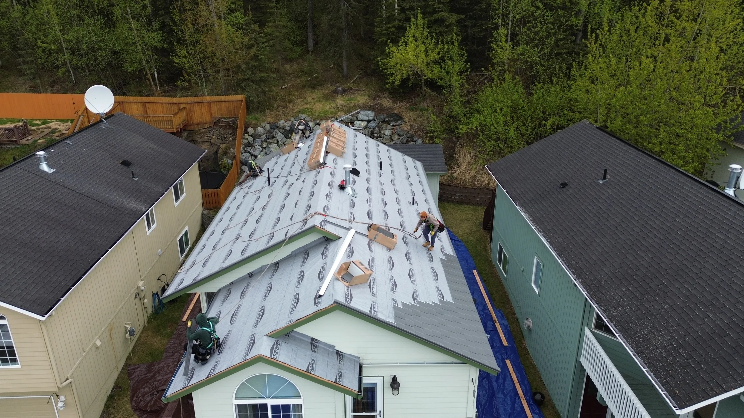 A metal roof being installed on a green house with a satellite dish on the roof