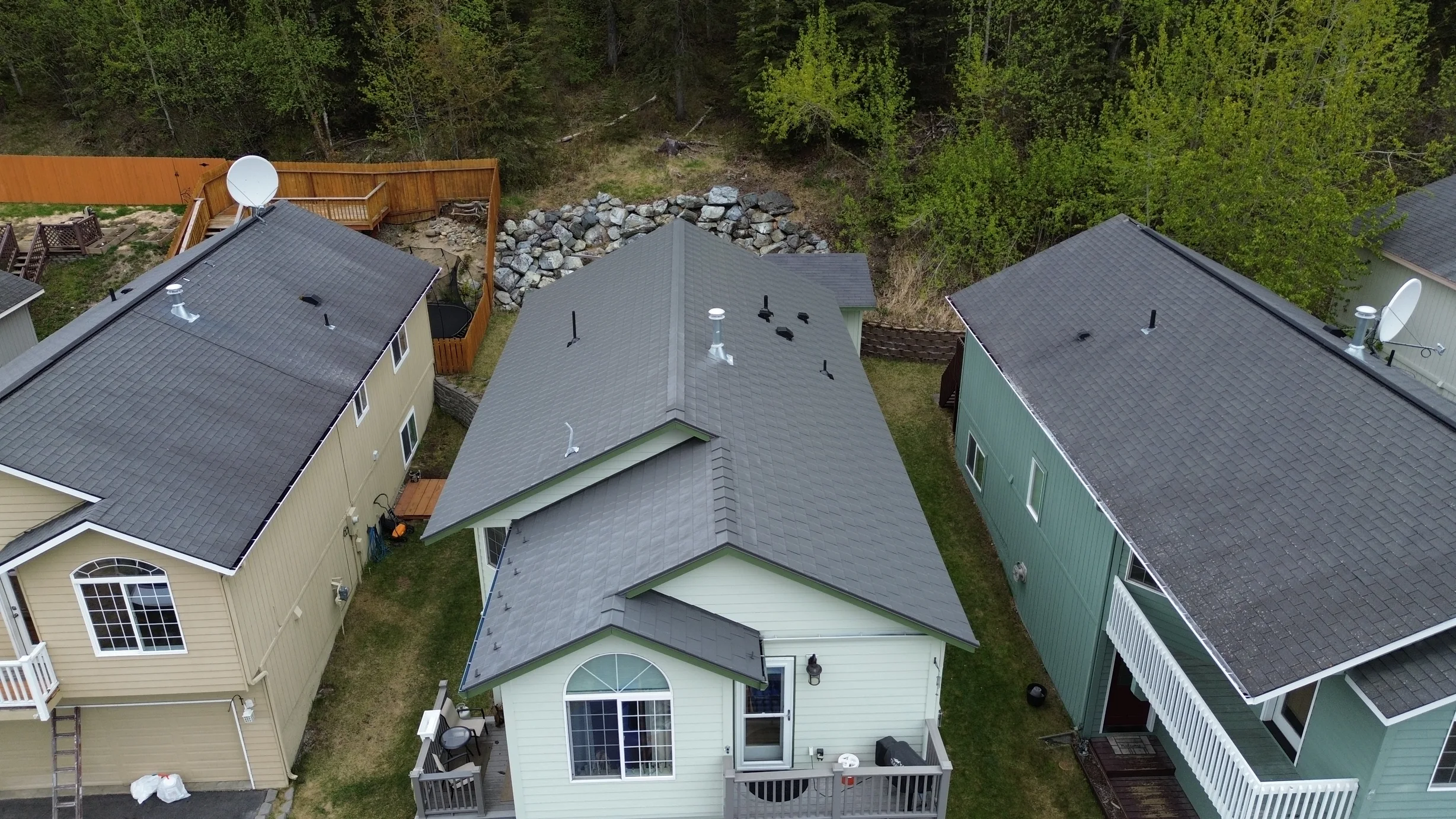 A ranch-style house with a metal roof in a forested rural area.