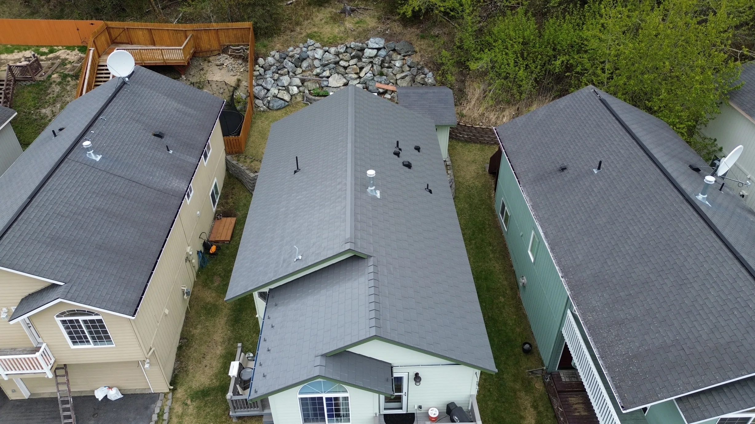 Aerial view of a house with a grey metal roof in a forested rural setting