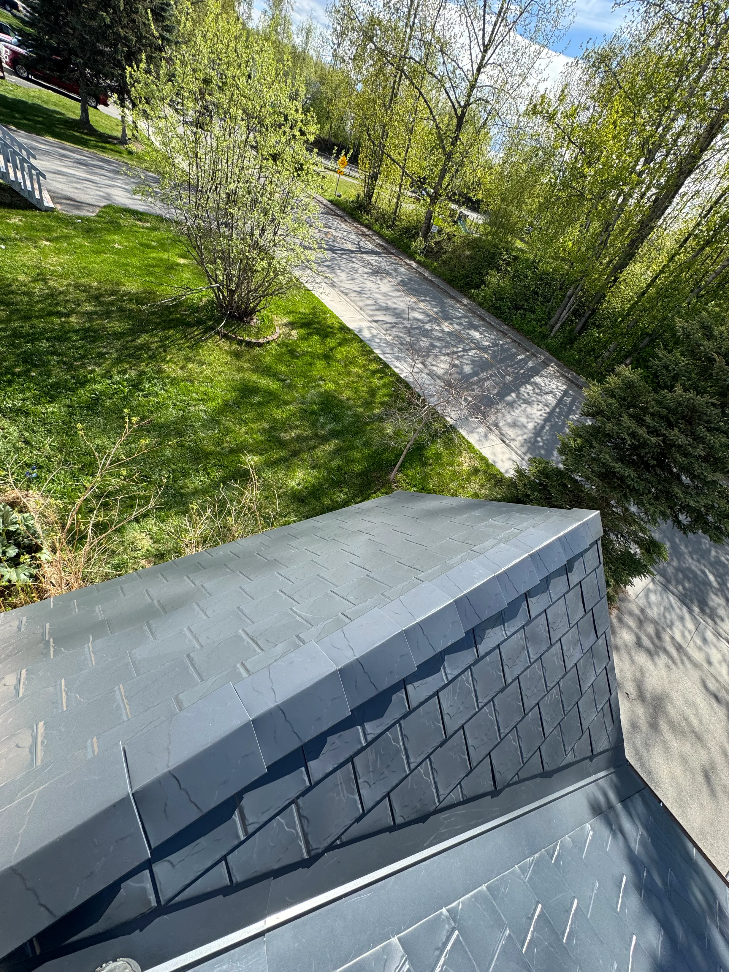 Modern metal roof with grey panels on a single-family home in an urban setting.