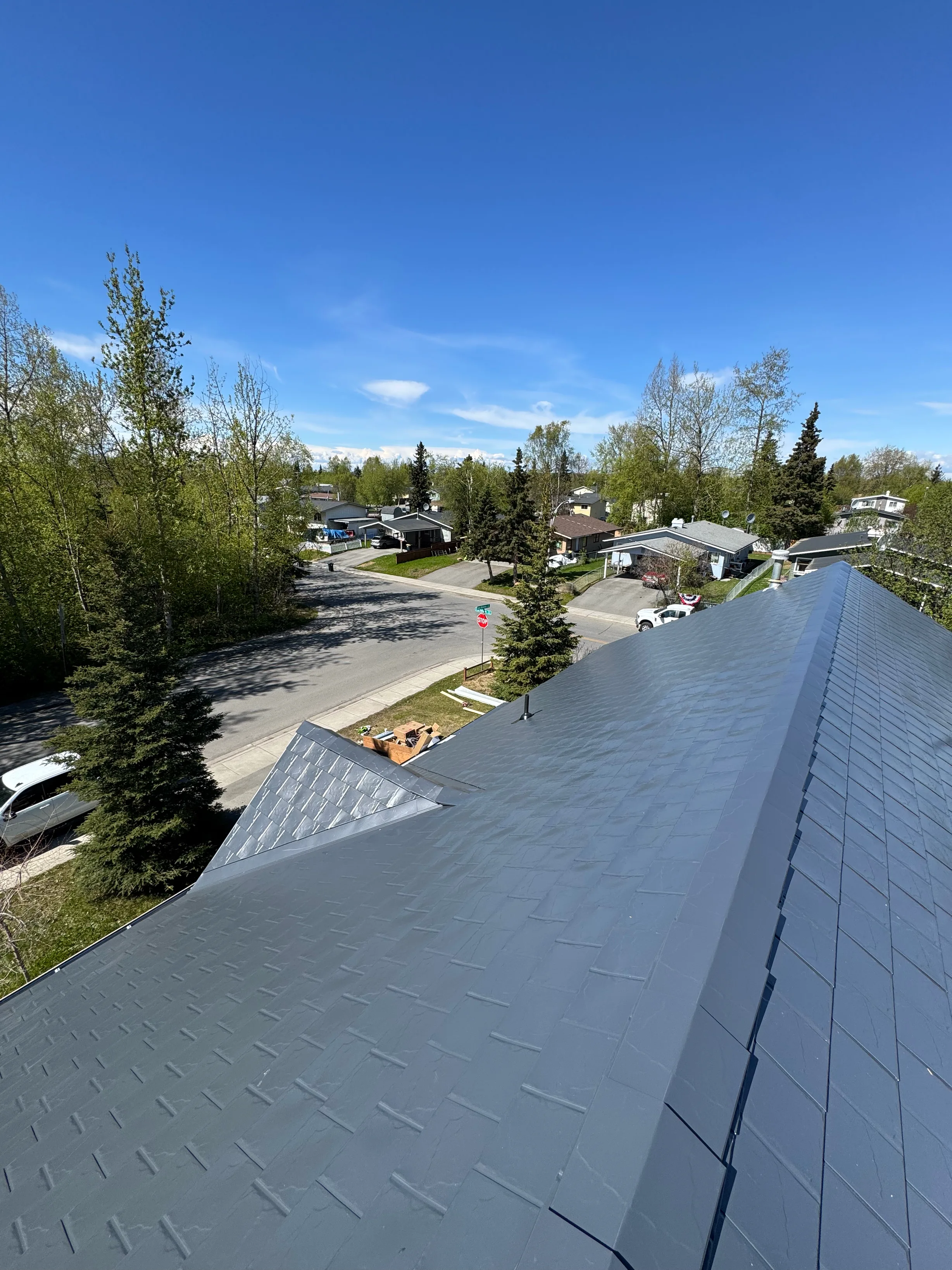A modern single-family home with a grey metal roof and a blue sky.
