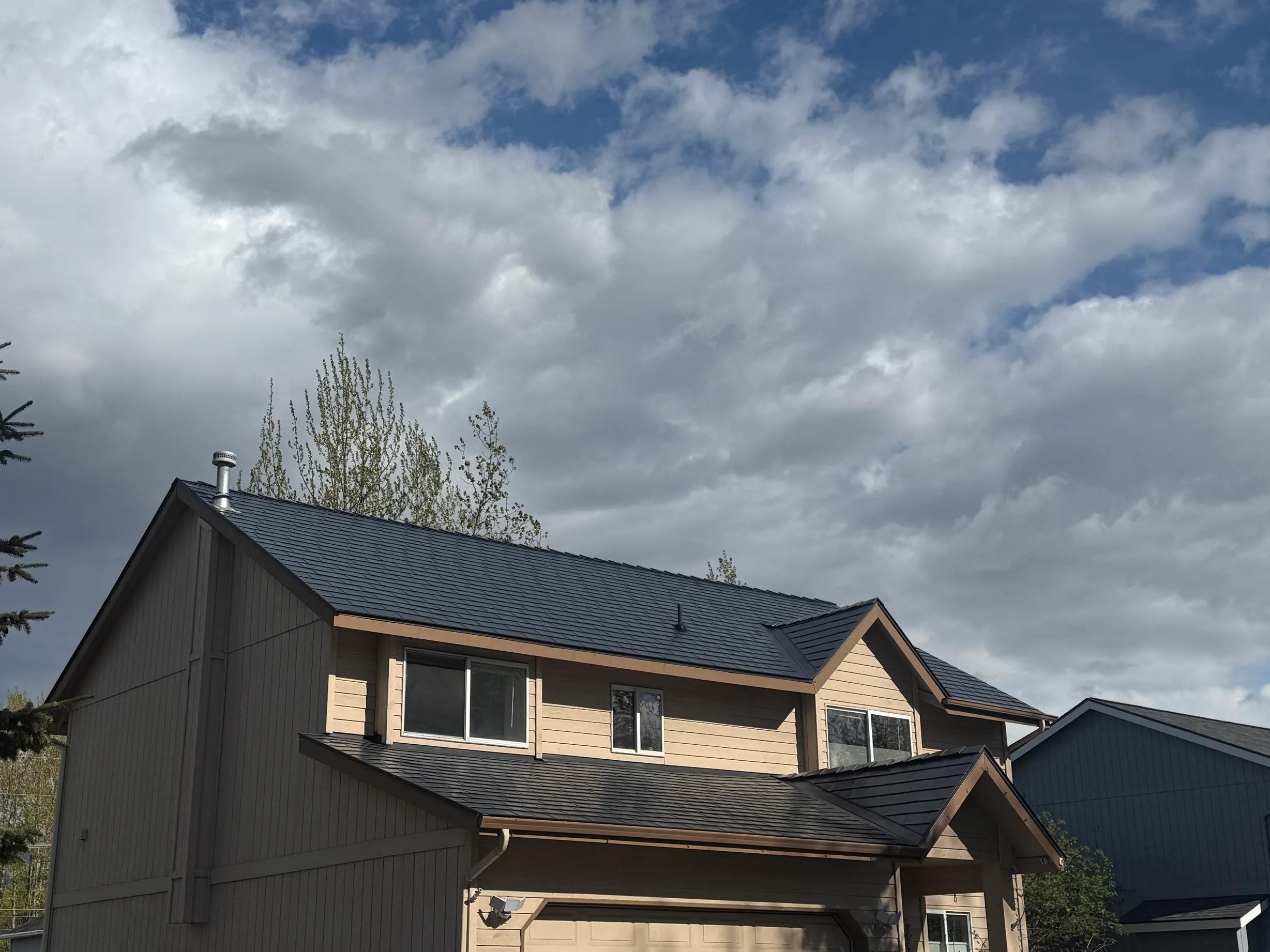 A modern-style single-family home with a finished metal roof under an overcast sky.