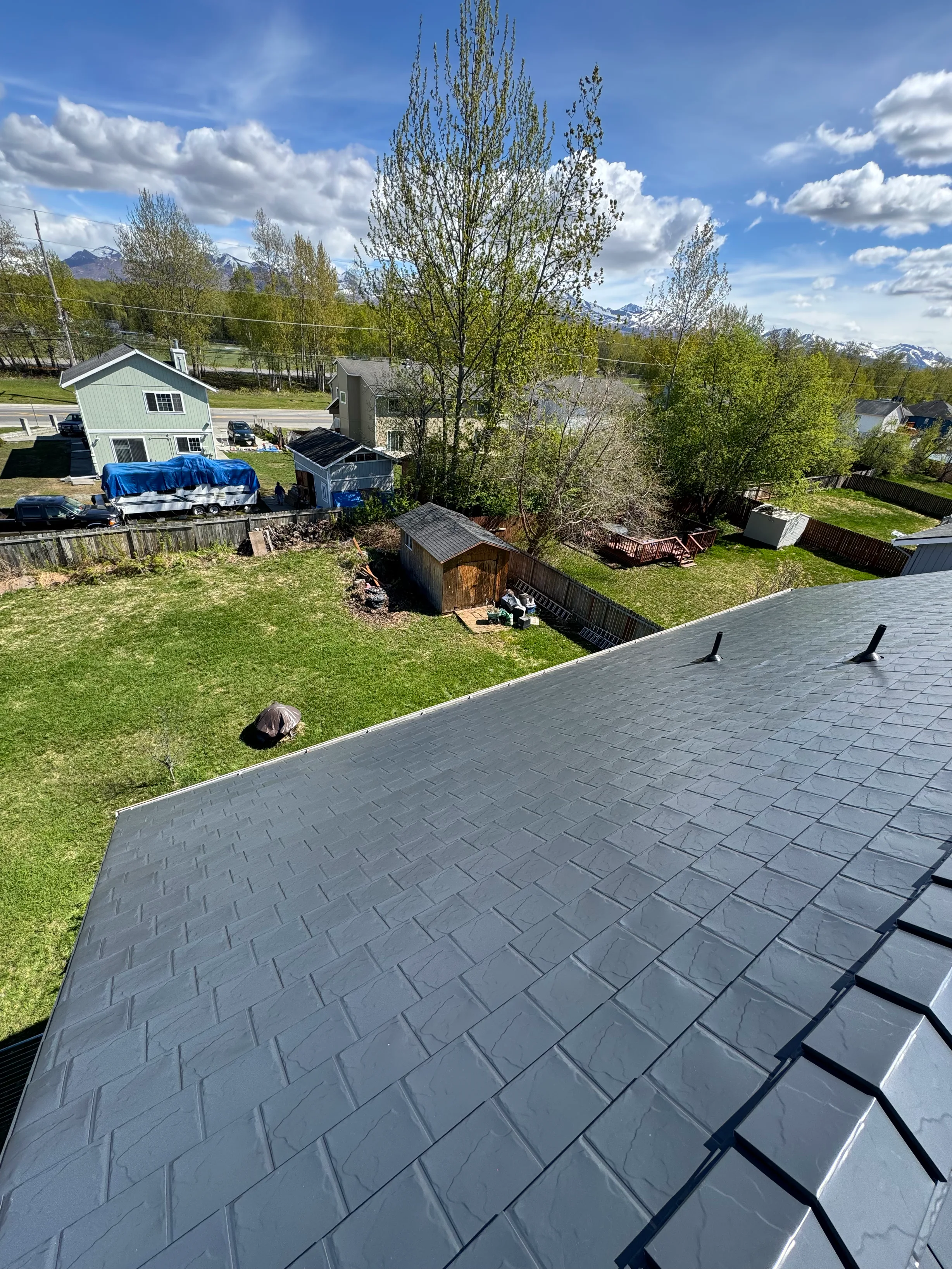 A grey metal roof on a single-story home in a rural setting.