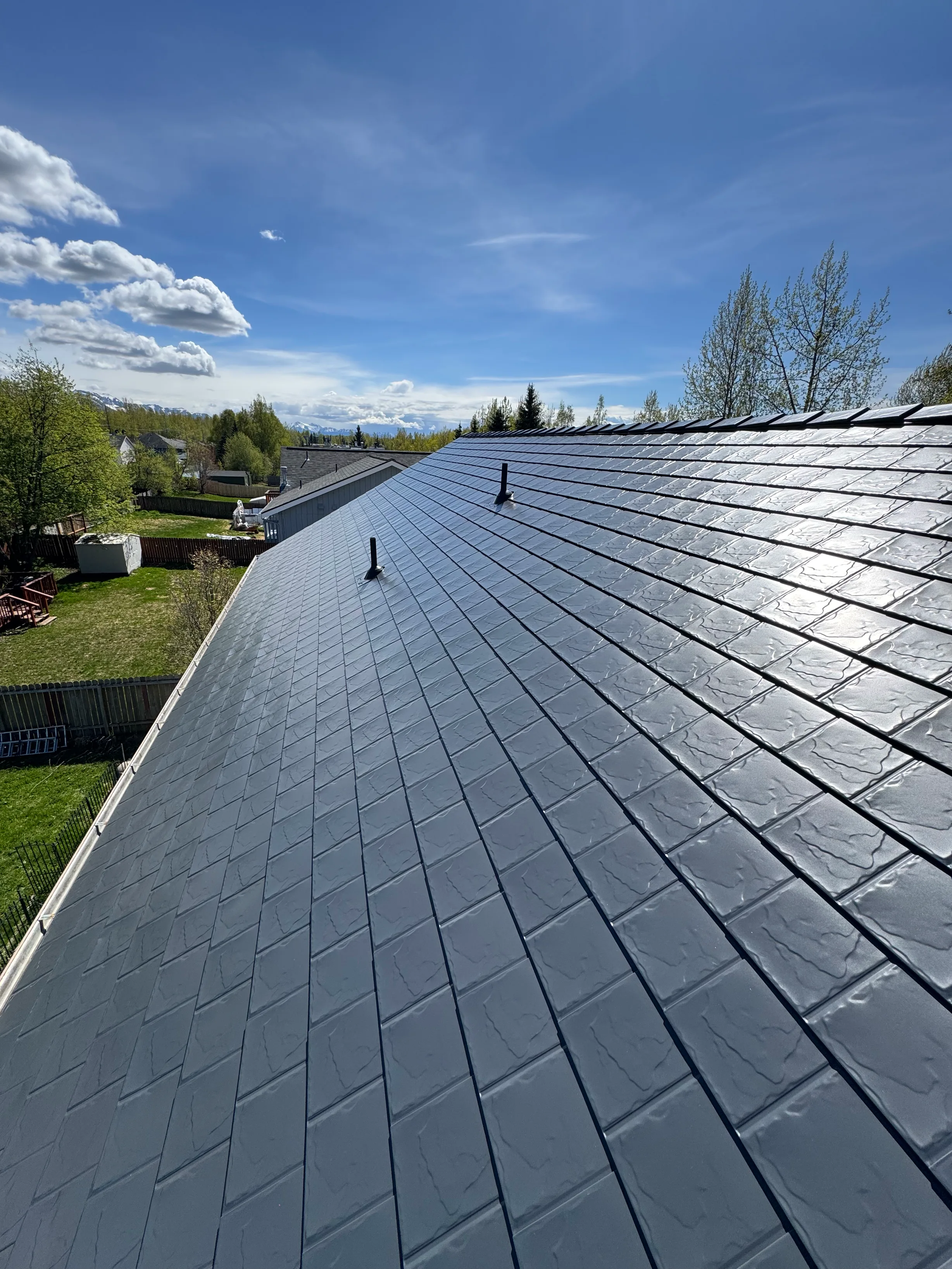 A modern metal roof in a suburban setting with lush greenery.