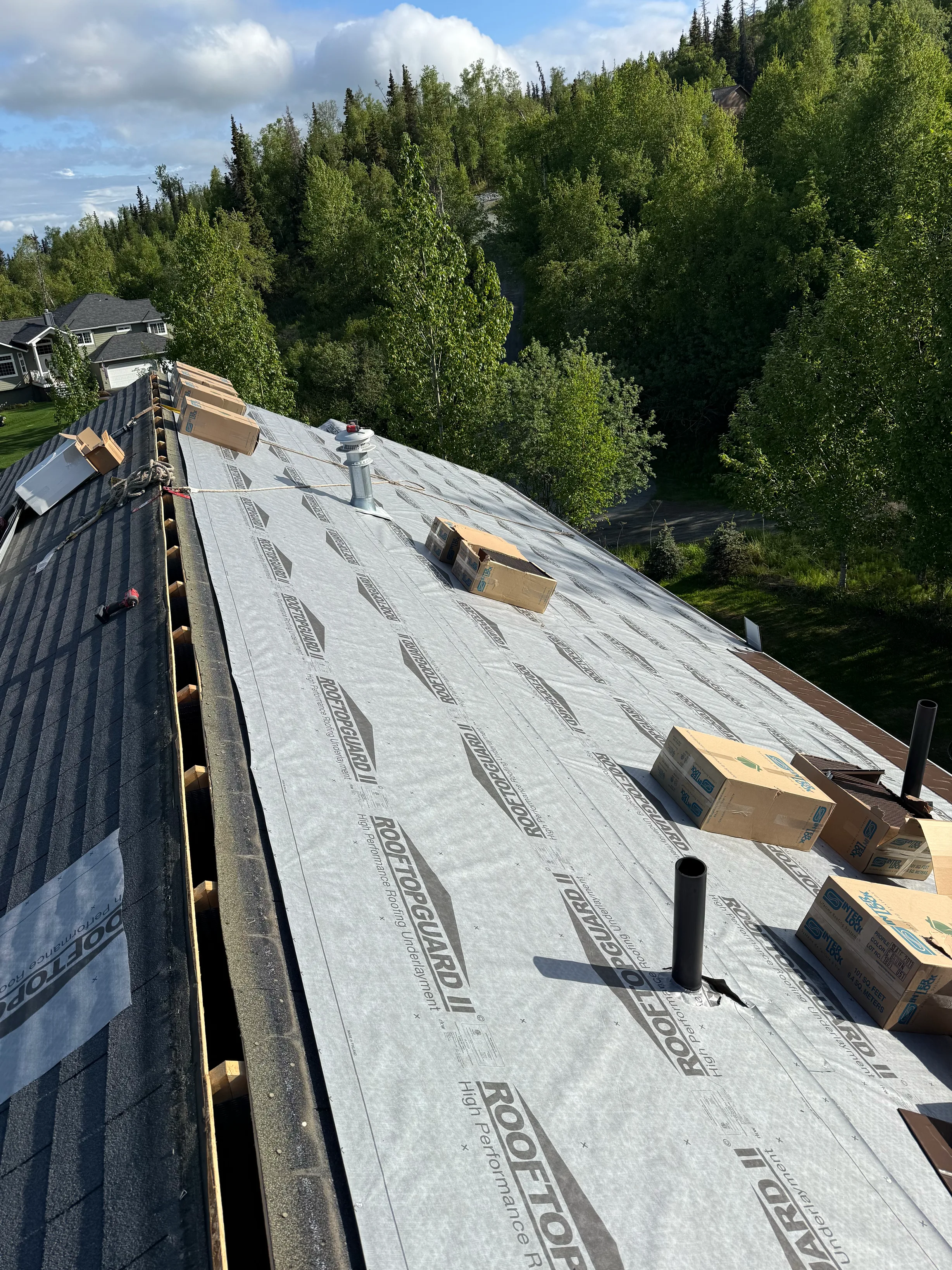 Metal roof underlayment installed on a modern single-family home in a forested rural setting