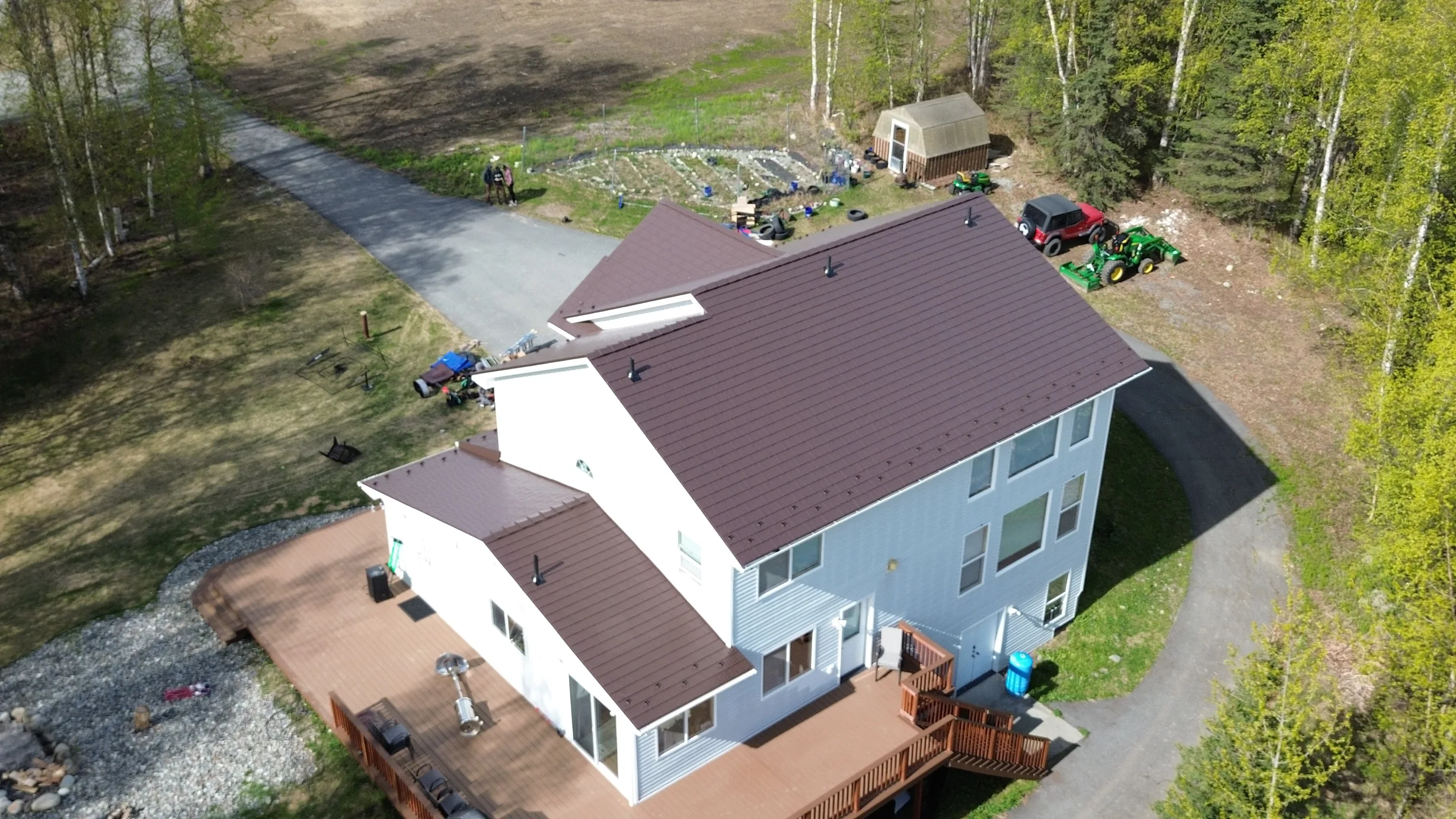 Metal roof with a dark brown finish on a modern single-family home in a forested rural area