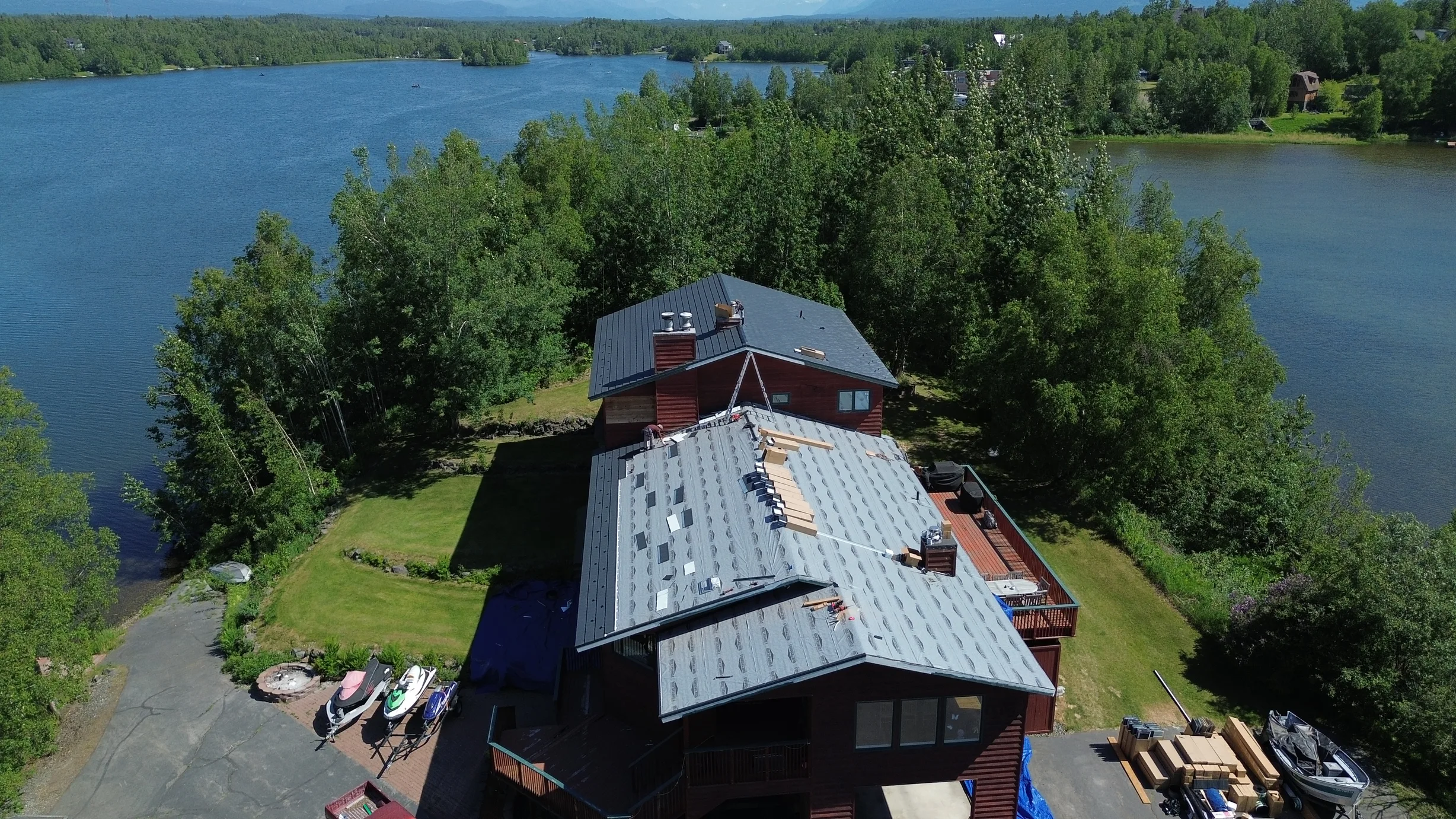 Aerial view of a finished metal roof with a lake in the background