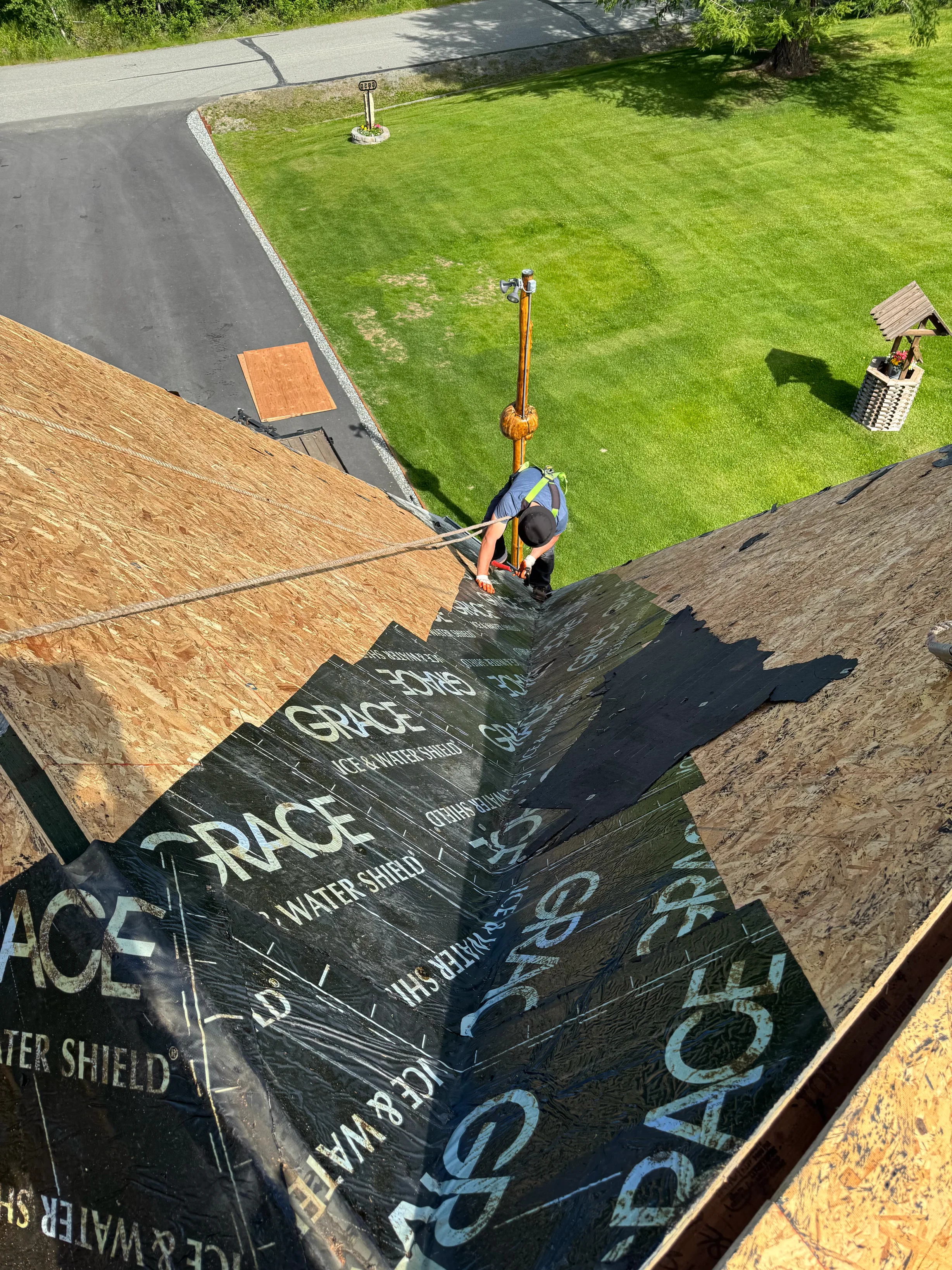 A modern metal roof under construction in an urban area with lush greenery and blue sky
