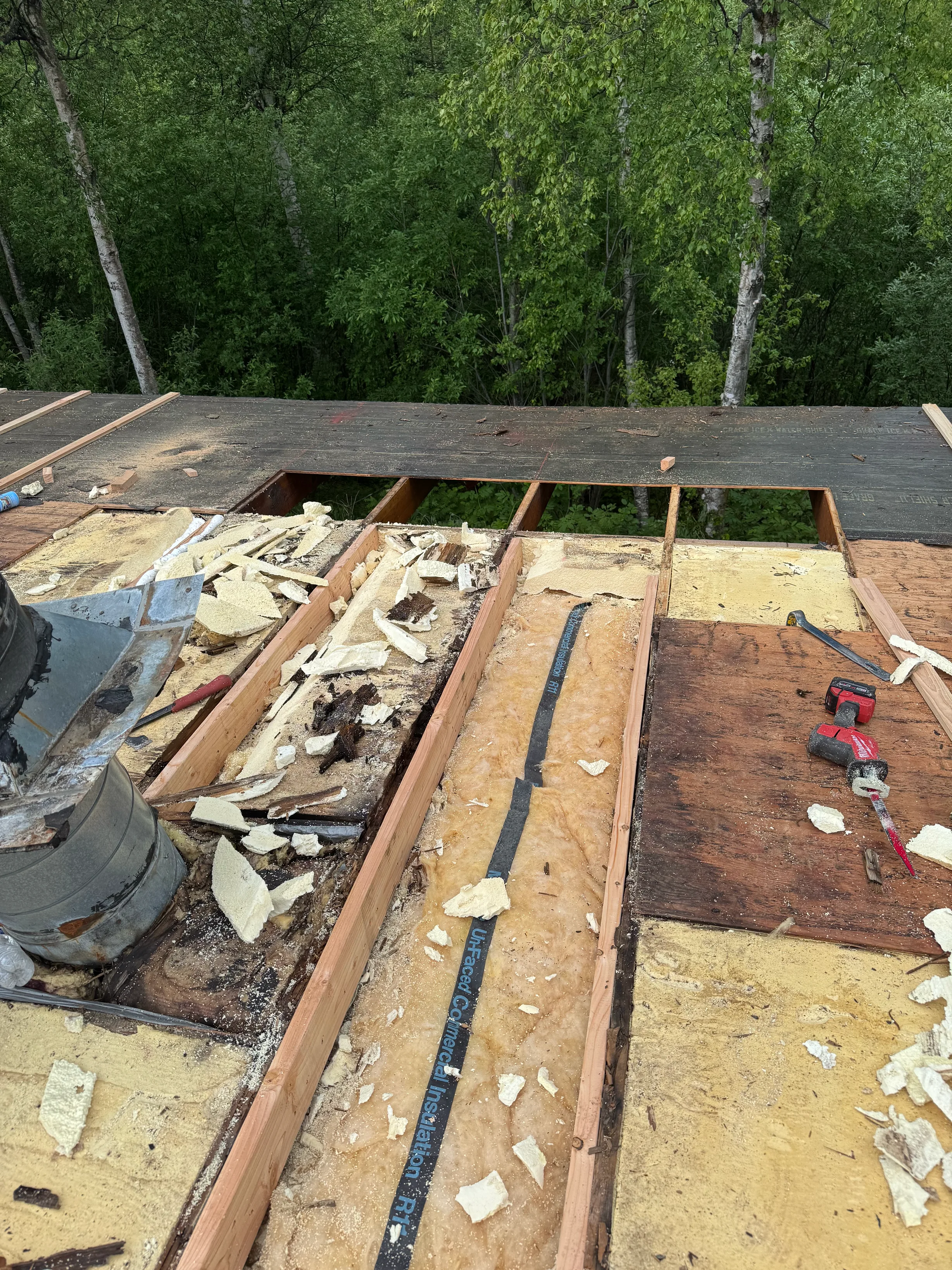 A metal roof under construction in a forested area.