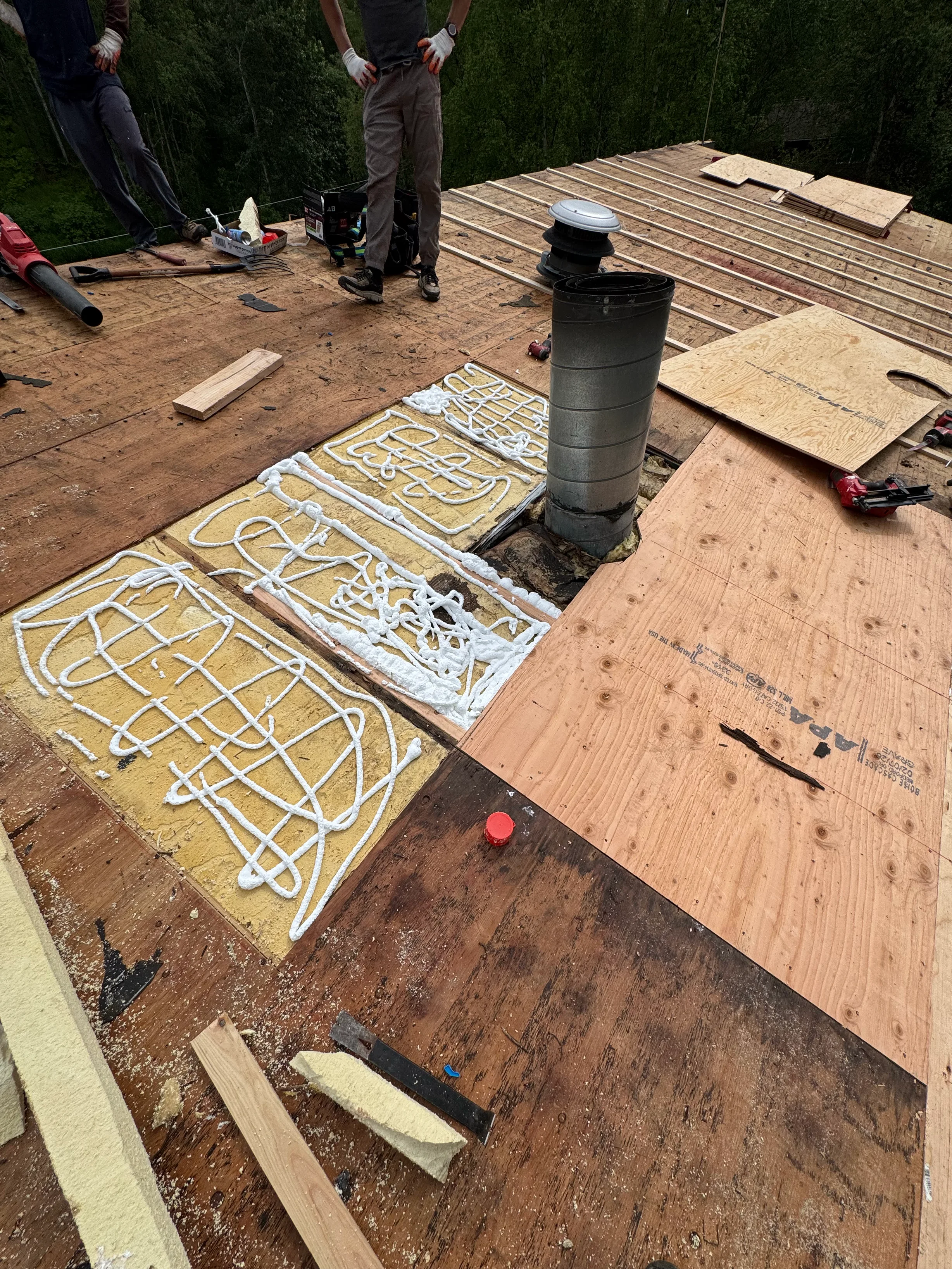 A modern metal roof being installed on a single-family home in a forested mountain setting.