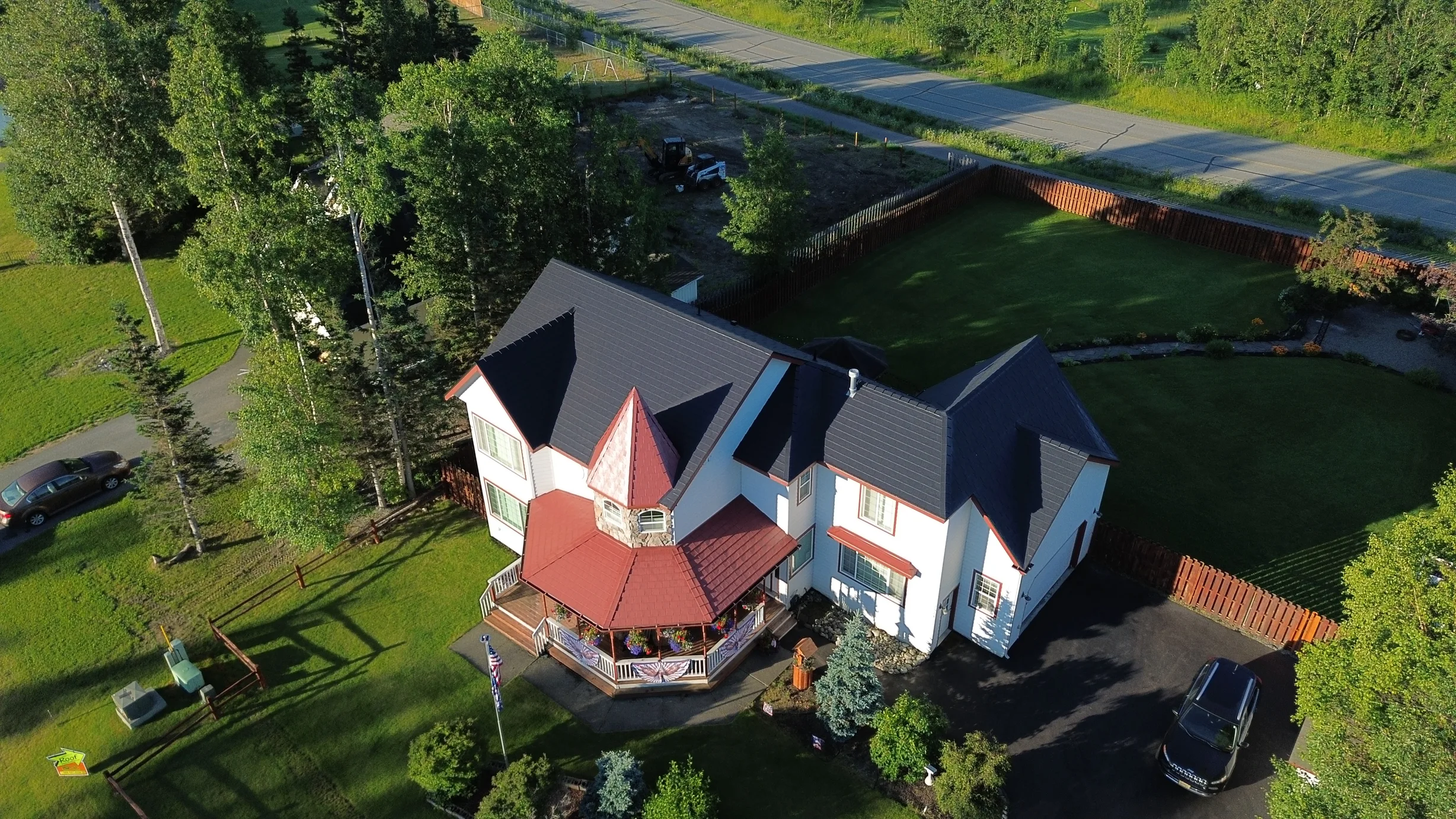 Aerial view of a modern single-family home with a finished metal roof in a rural forested setting.