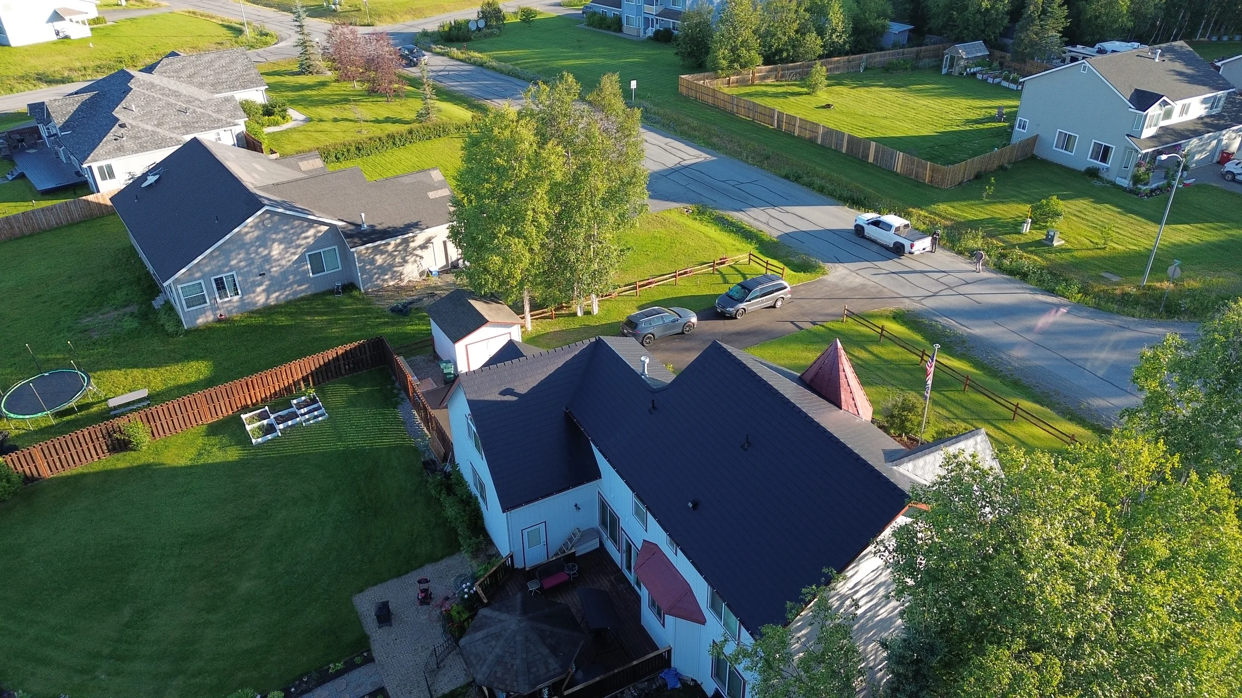 A ranch-style house with a black metal roof in a wooded, rural area