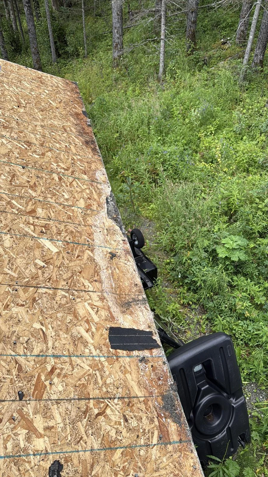 A metal roof being installed on a rural home surrounded by lush greenery.