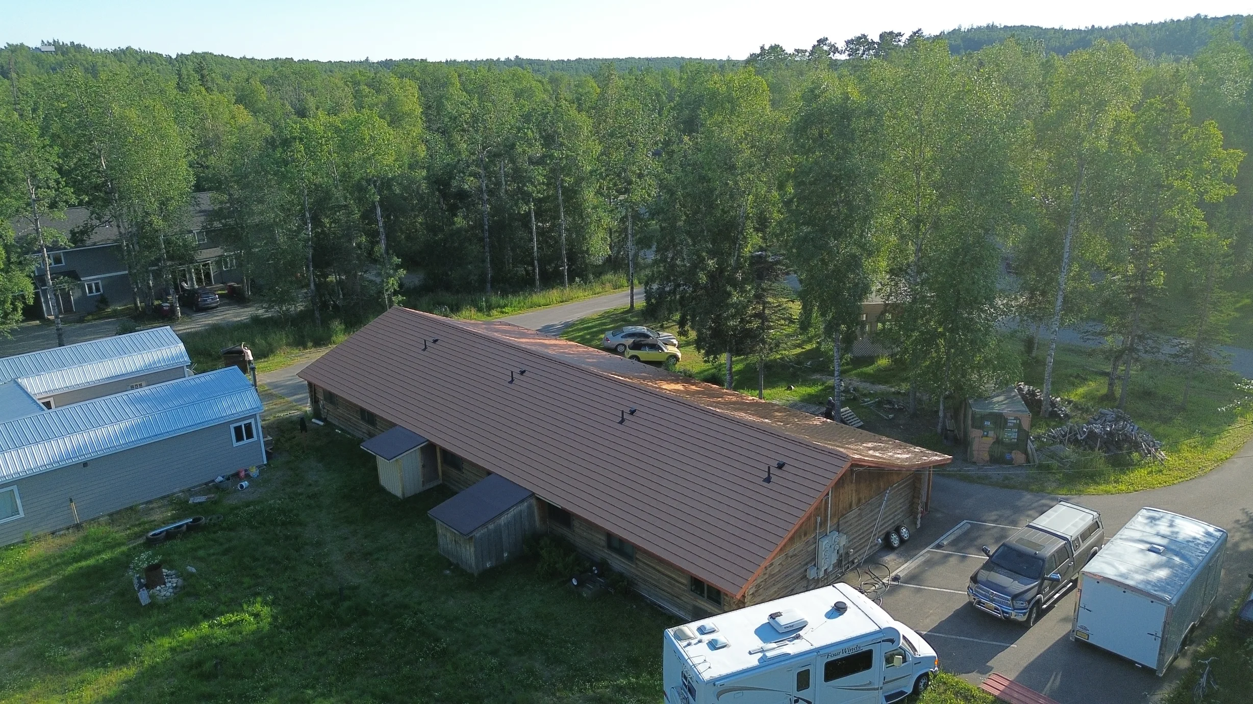 Aerial view of a ranch style home with a brown metal roof and a white RV parked in the driveway.