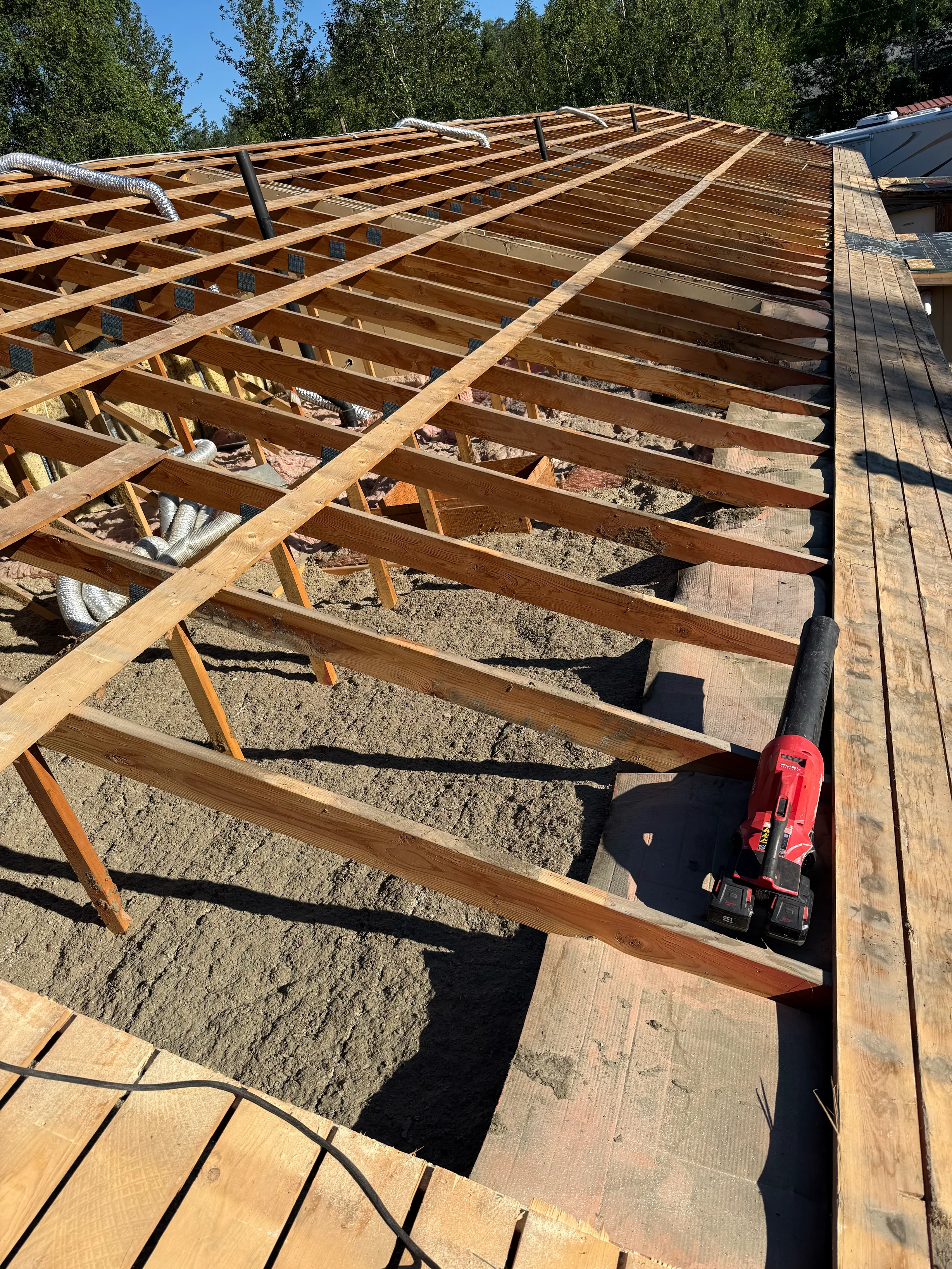 A modern metal roof being installed on a single-family home in a forested area.
