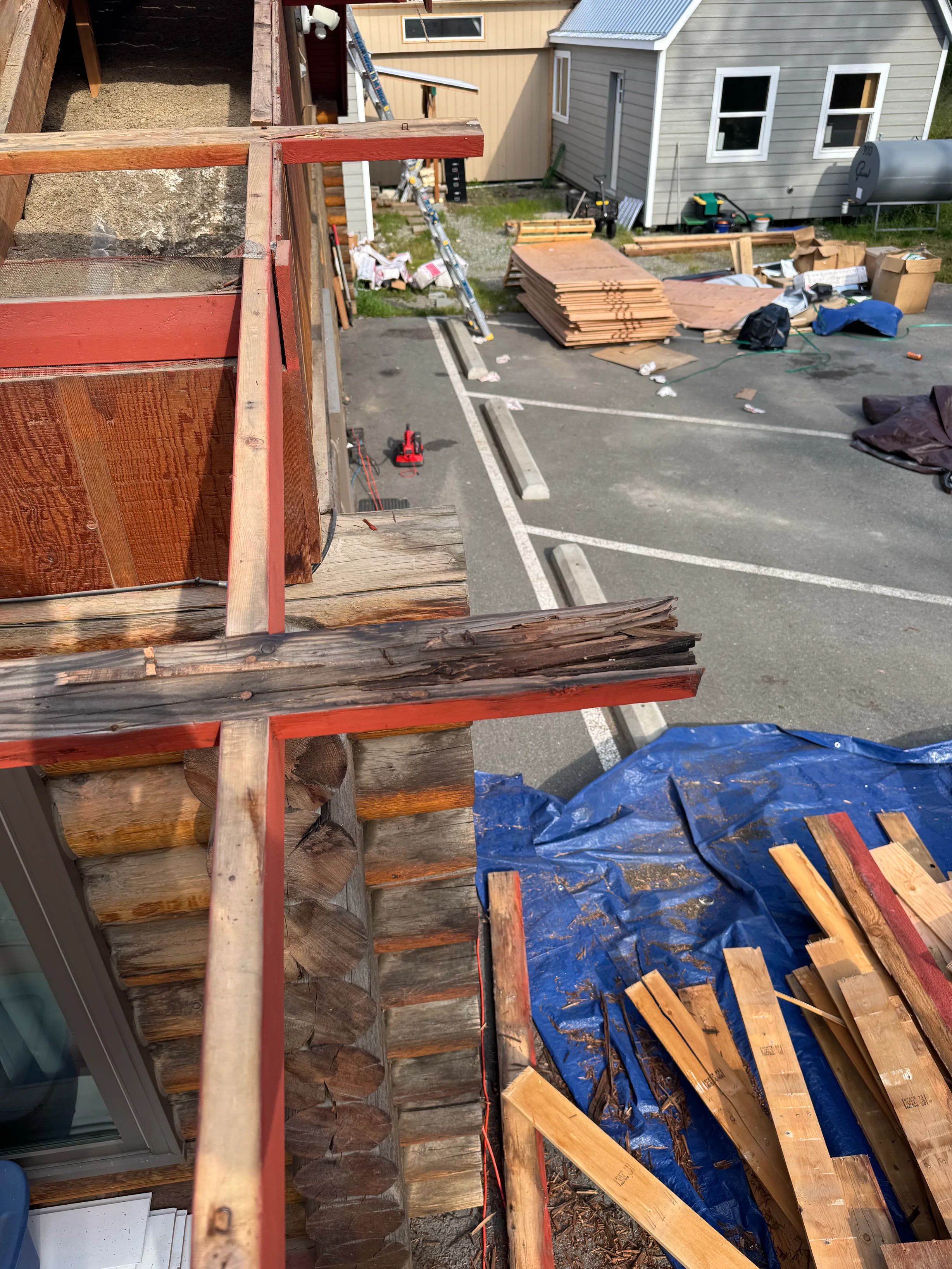A metal roof being installed on a craftsman-style single-family home in a forested rural area on a sunny day.