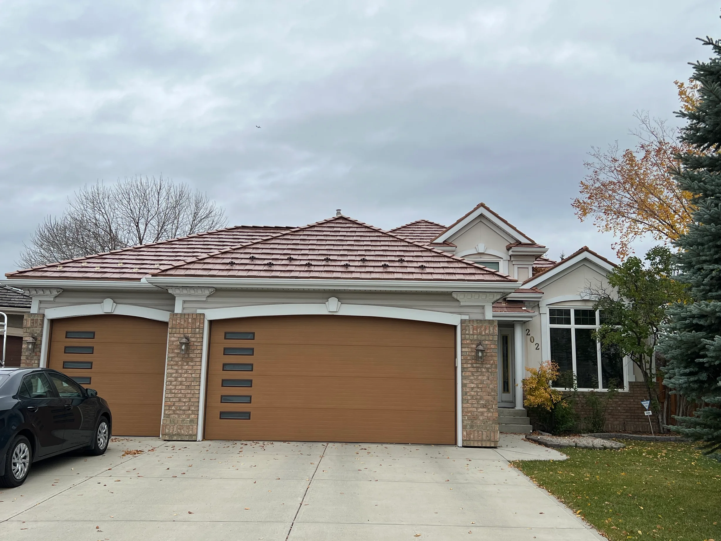Aged Copper Interlock Shake aluminum roof on a two-storey home with brick and stone accents in a, Calgary, Alberta