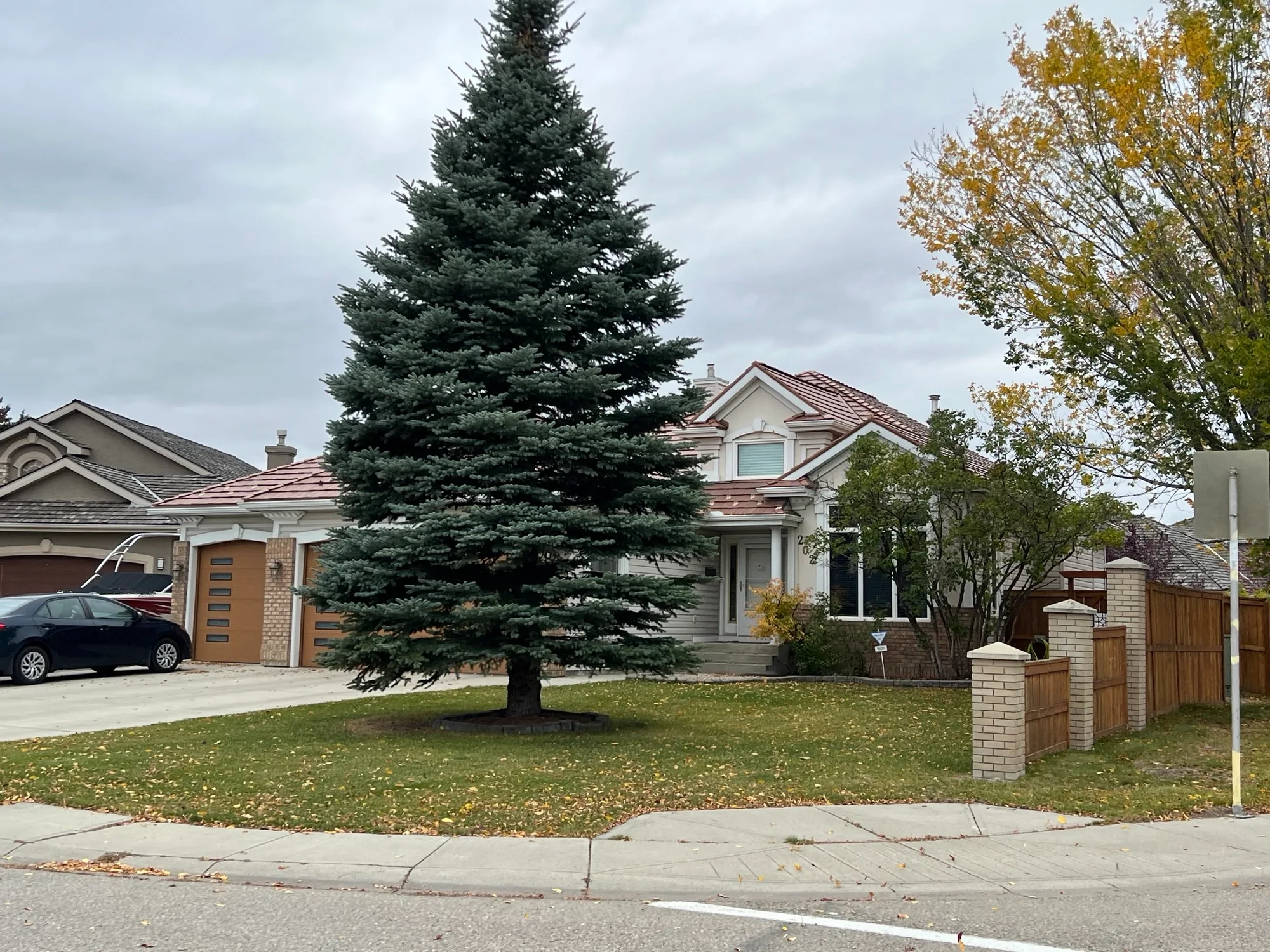 Aged Copper Interlock Shake aluminum roof on a grey two-storey home with dormers and a metal roof in an, Calgary, Alberta