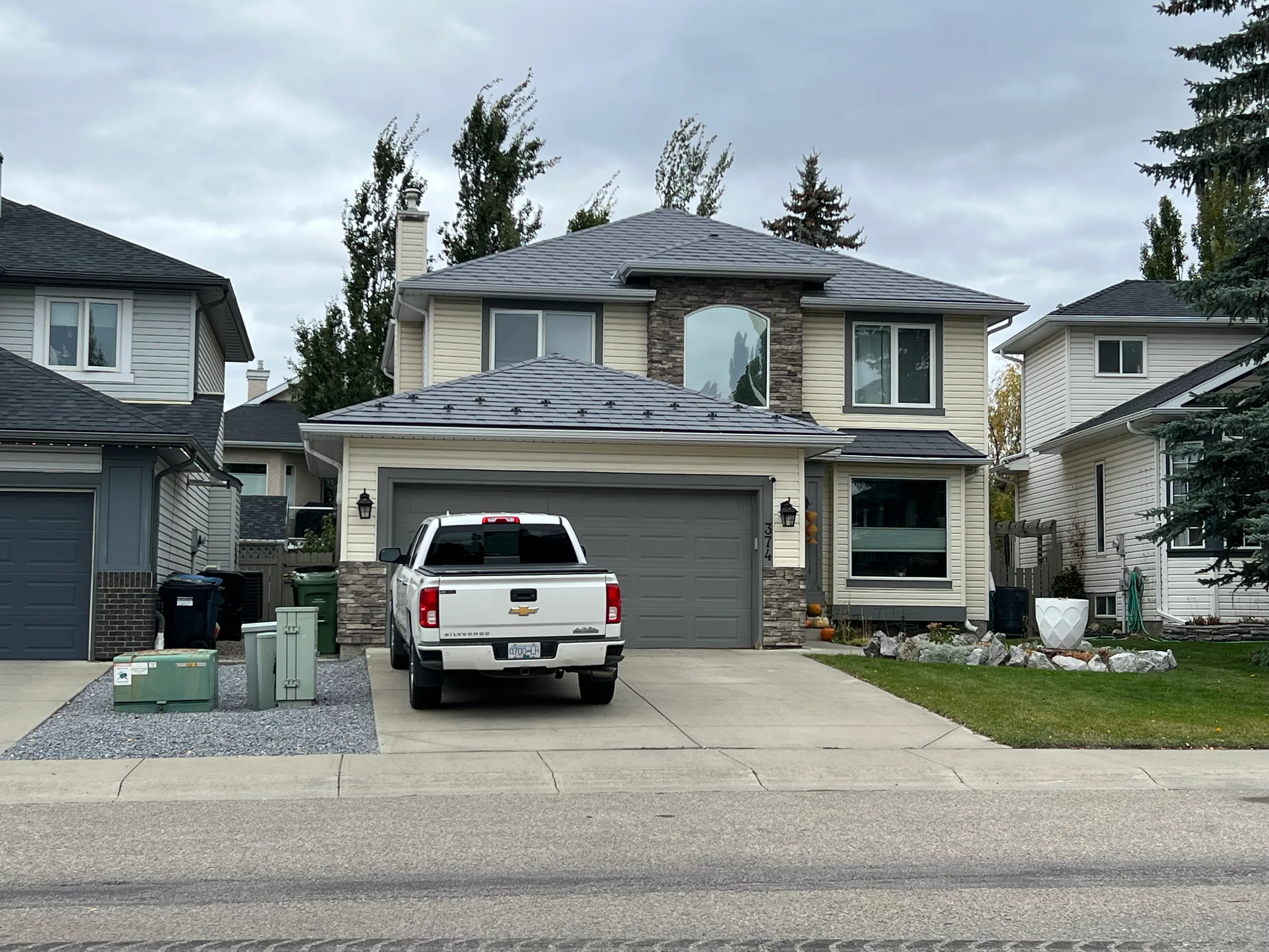 Charcoal Grey Interlock Slate aluminum roof on a beige two-storey home with stone accents in a suburban, Calgary, Alberta