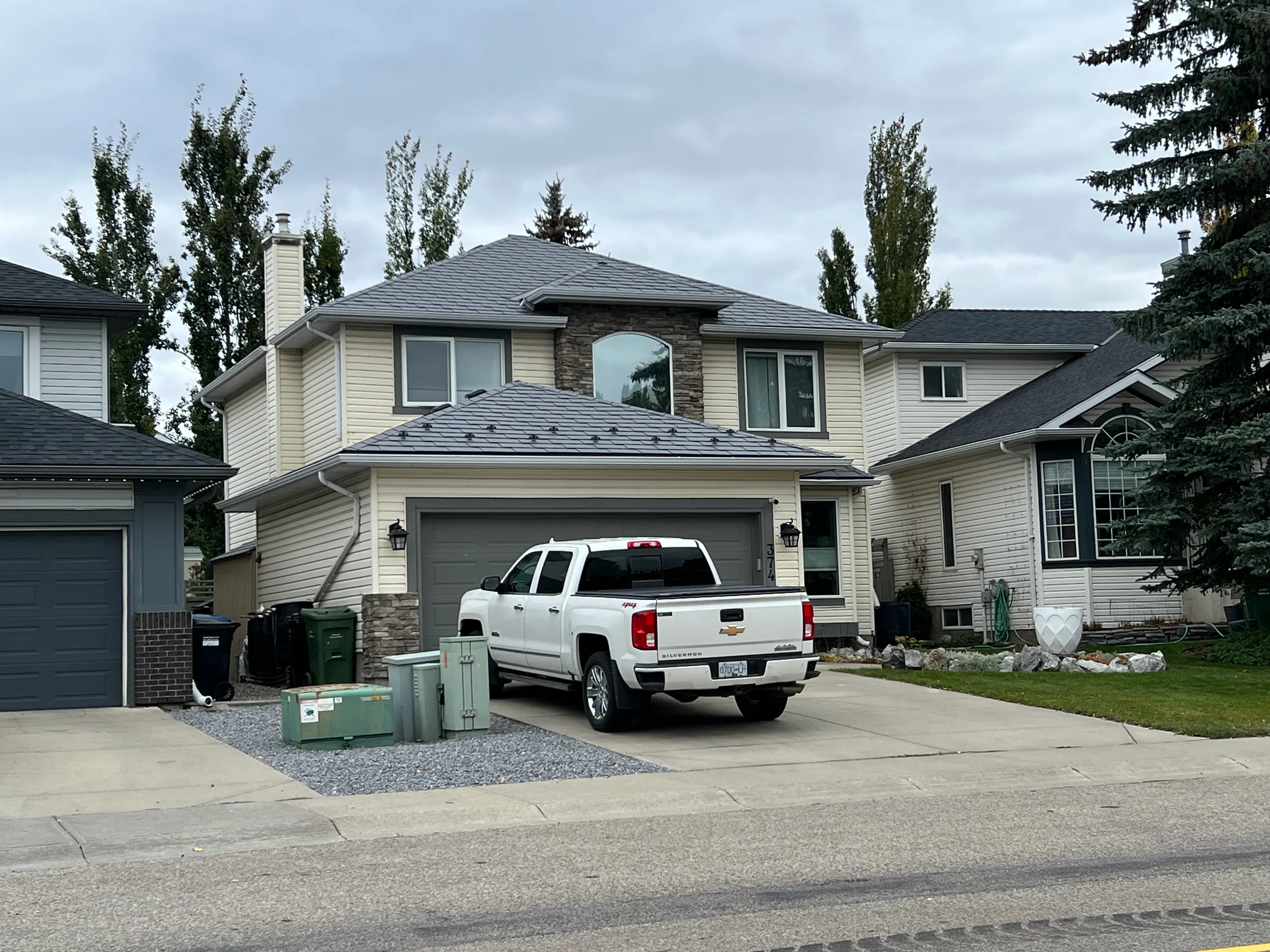 Charcoal Grey Interlock Slate aluminum roof on a beige two-storey home with dormers and a metal roof, Calgary, Alberta