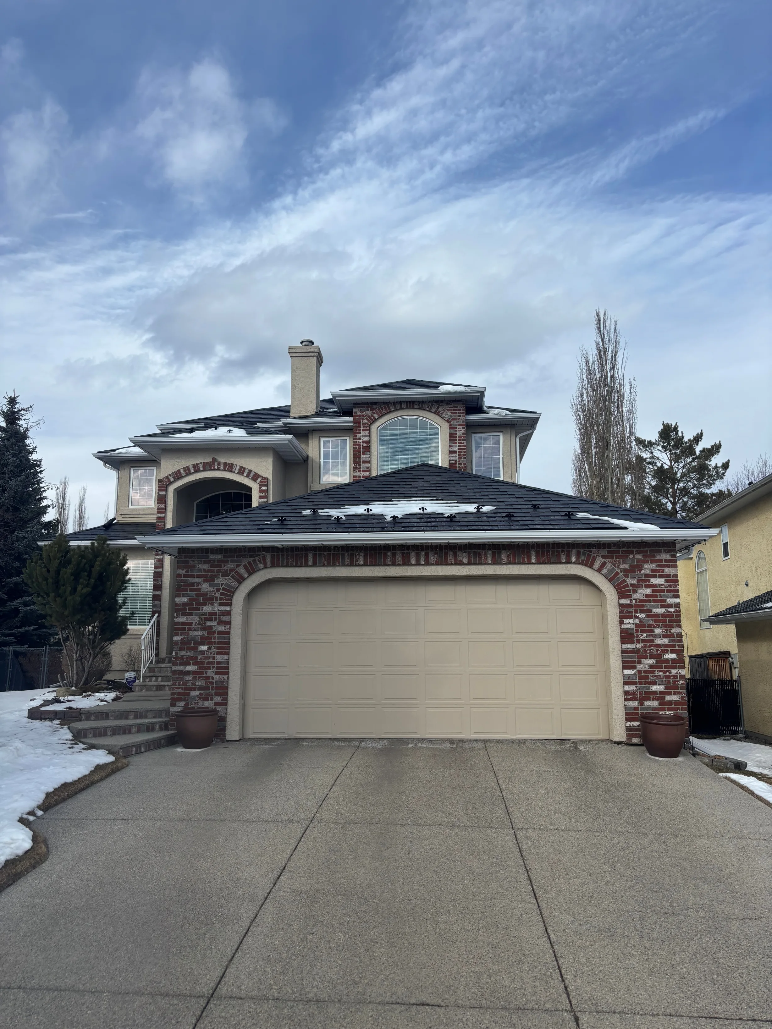Black Interlock Slate aluminum roof on a two-storey home with a metal roof and brick accents in a, Calgary, Alberta