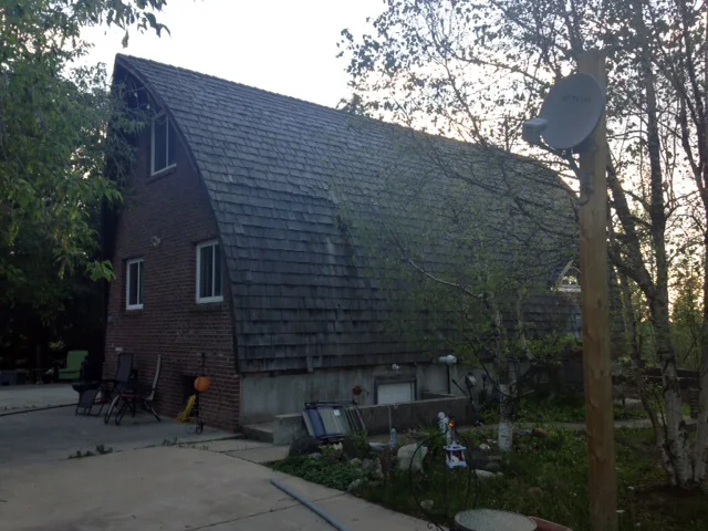 Black Interlock Slate aluminum roof on a brown single-storey home with a metal roof among trees, Whitecourt, Alberta