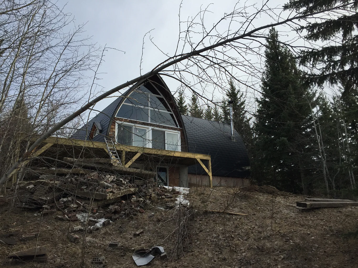 Black Interlock Slate aluminum roof on a brown A-frame home with a black metal roof in a forest, Whitecourt, Alberta