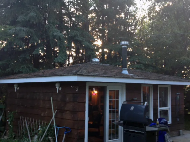 Black Interlock Slate aluminum roof on a brown ranch home with chimney among tall trees, Whitecourt, Alberta
