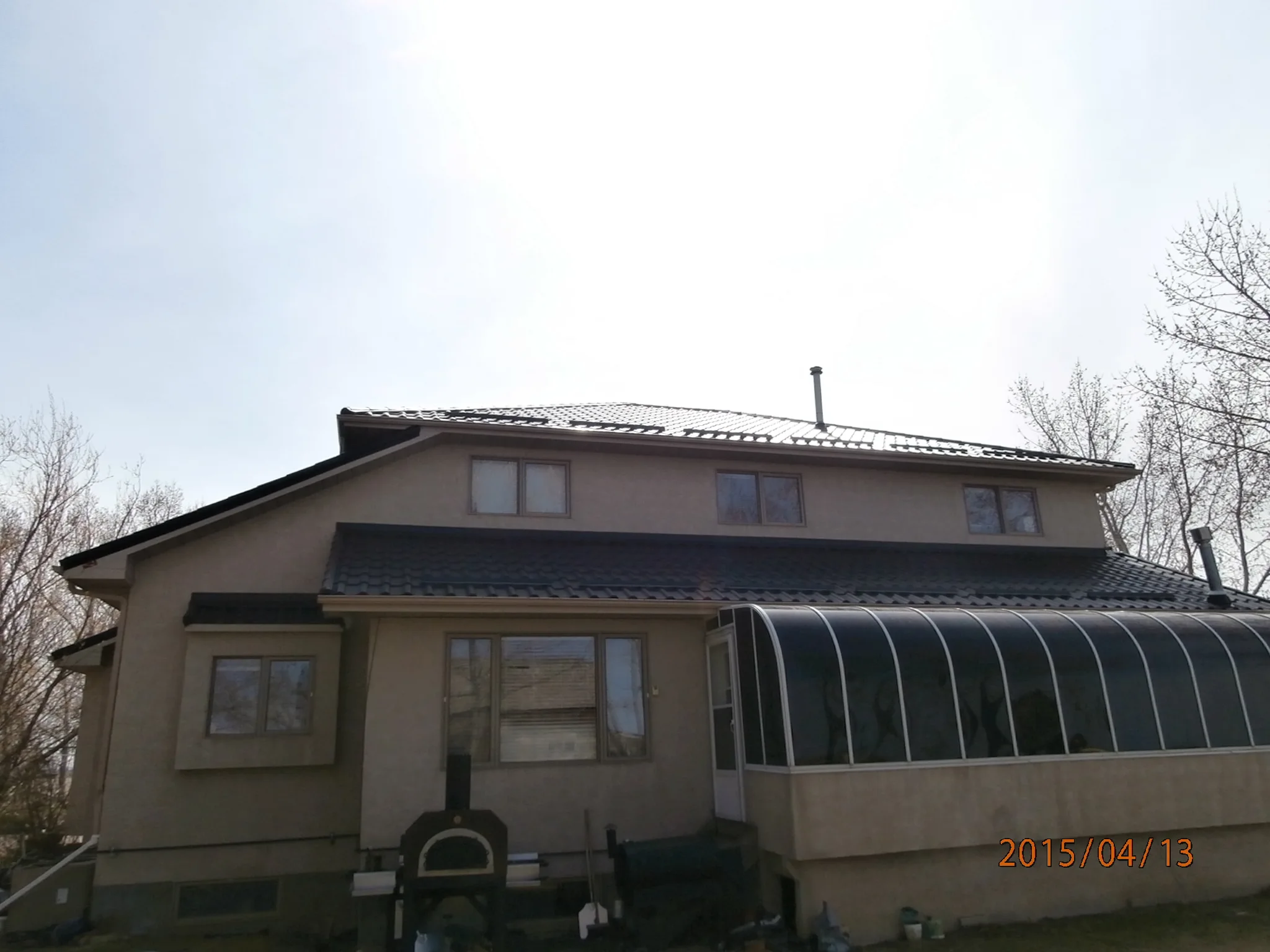 Black Interlock Tile aluminum roof on a tan single-storey home with a metal roof in rural Alberta, Redcliff, Alberta