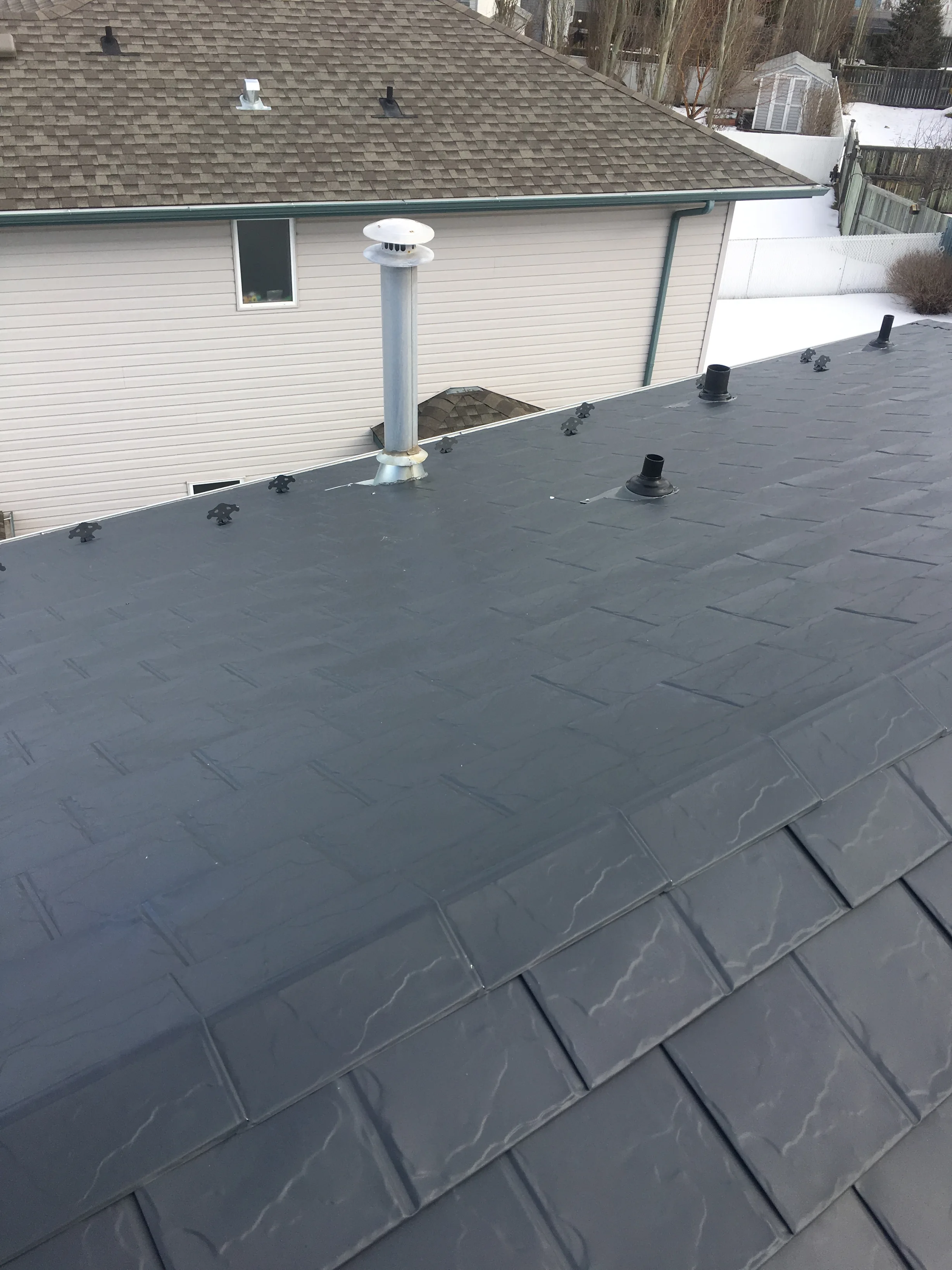 Deep Charcoal Interlock Slate aluminum roof on a single-storey modern home in a snow-covered rural setting, Fort Saskatchewan, Alberta
