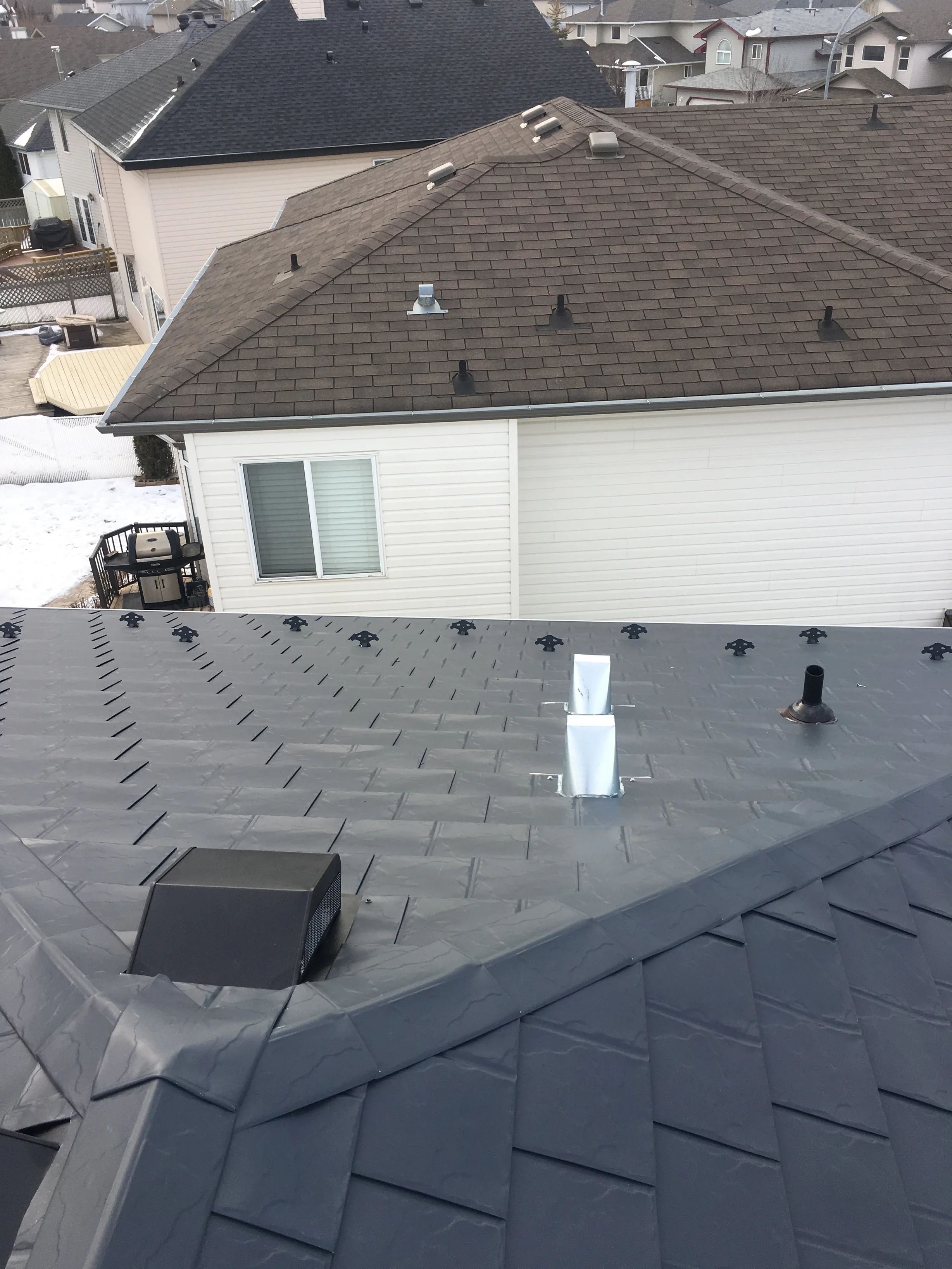 Deep Charcoal Interlock Slate aluminum roof on a white ranch style home with a chimney among snow covered, Fort Saskatchewan, Alberta