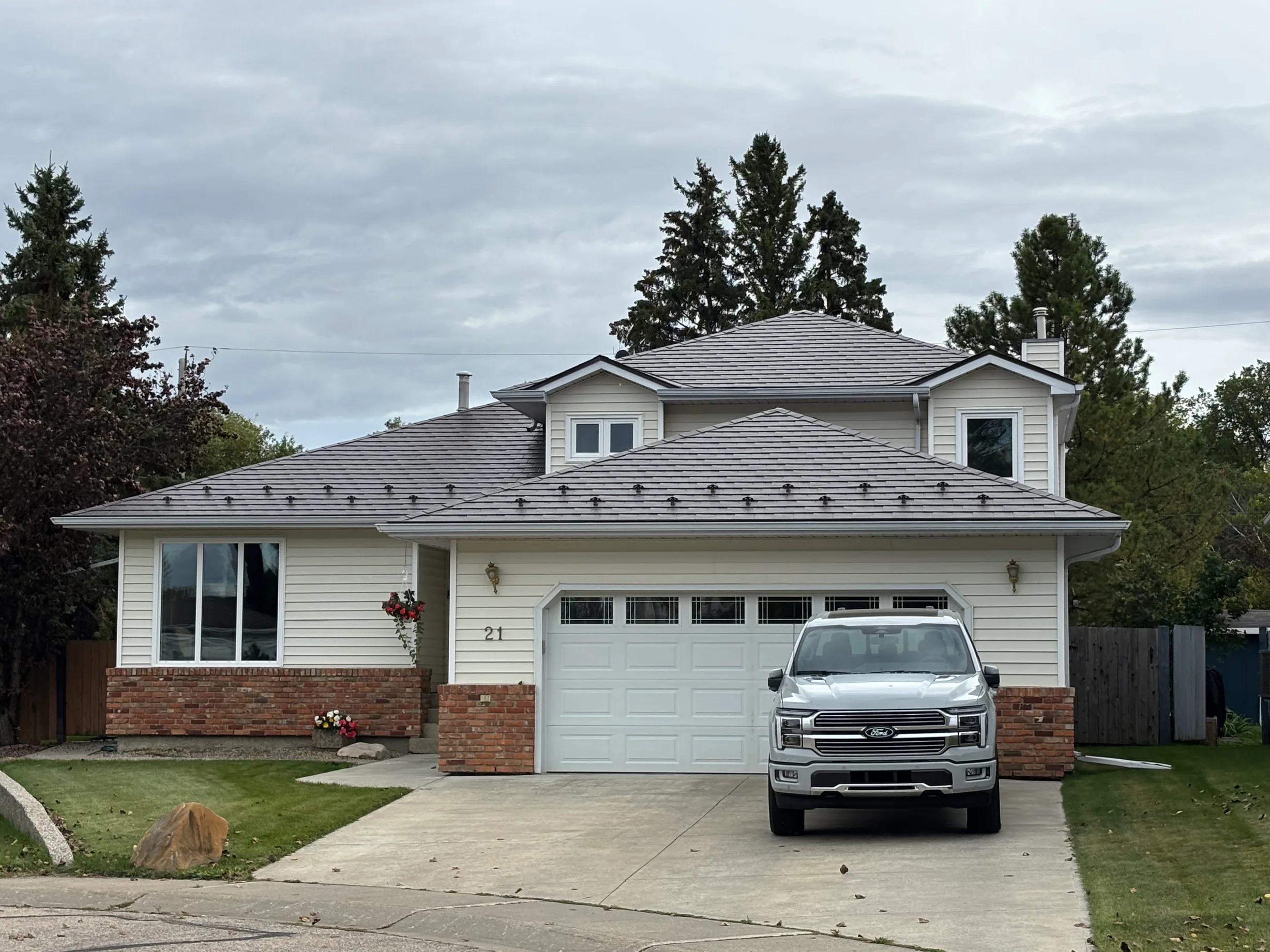 Tudor Brown Interlock Slate aluminum roof on a Tudor-style house with a brown roof in a rural area, Devon, Alberta