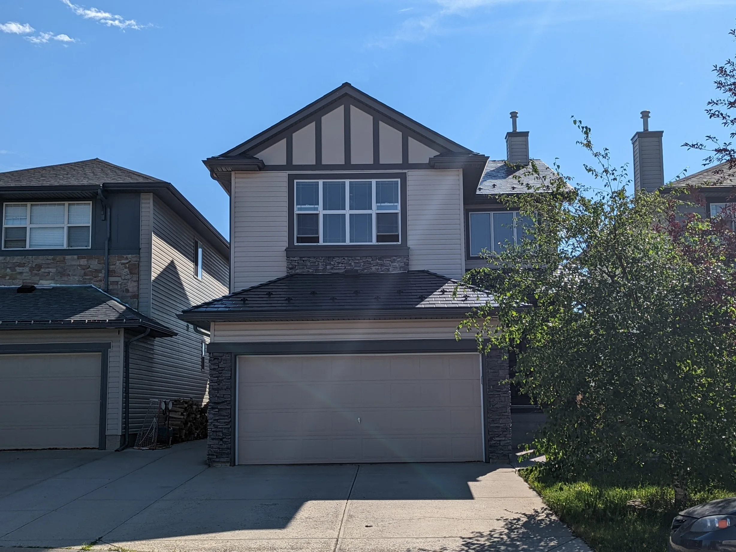 Black Interlock Slate aluminum roof on a two-storey home with dormers and metal roof among tall, Calgary, Alberta
