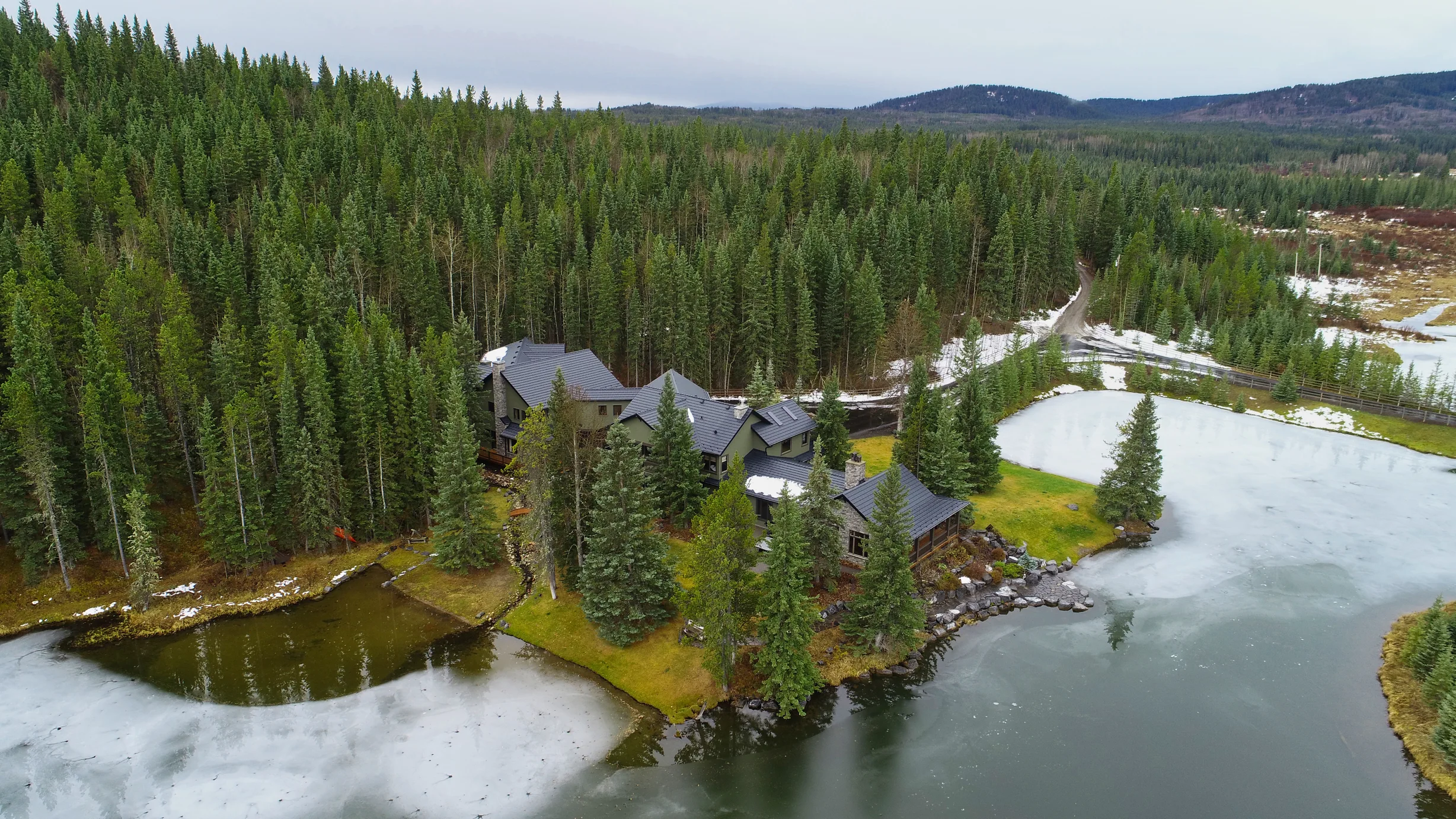 Black Interlock Shake aluminum roof on a black chalet-style home among tall pine trees, Bragg Creek, Alberta