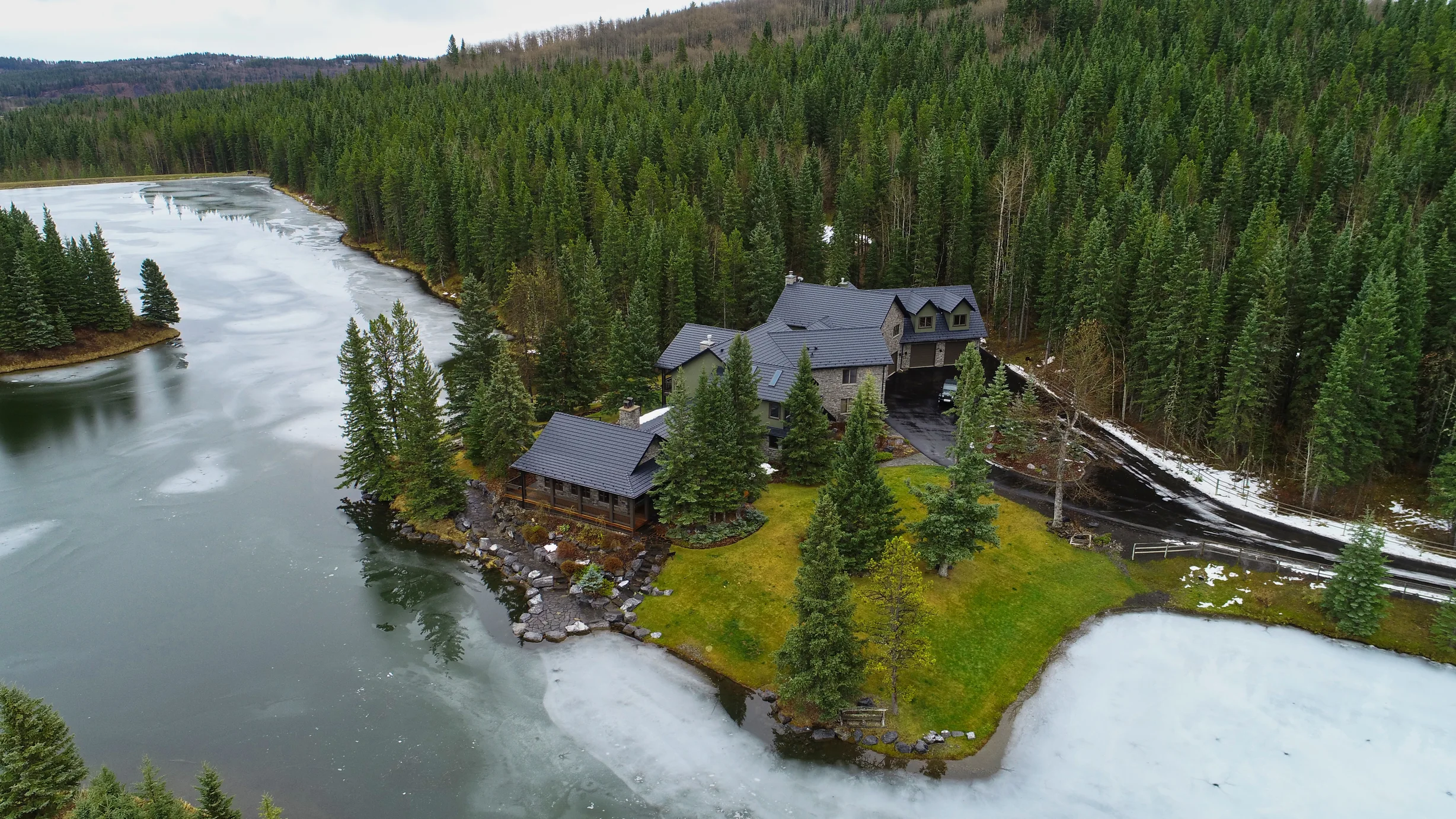 Black Interlock Shake aluminum roof on a metal roof on a chalet-style home among tall trees in the, Bragg Creek, Alberta