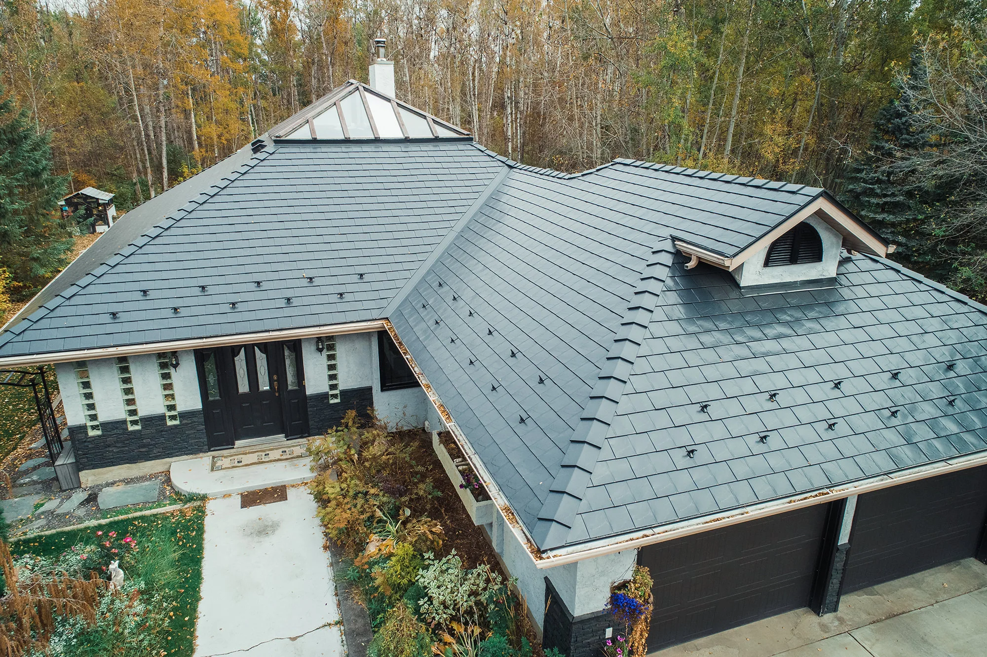 Black Interlock Slate aluminum roof on a modern home with a black metal roof among fall trees, Spruce Grove, Alberta