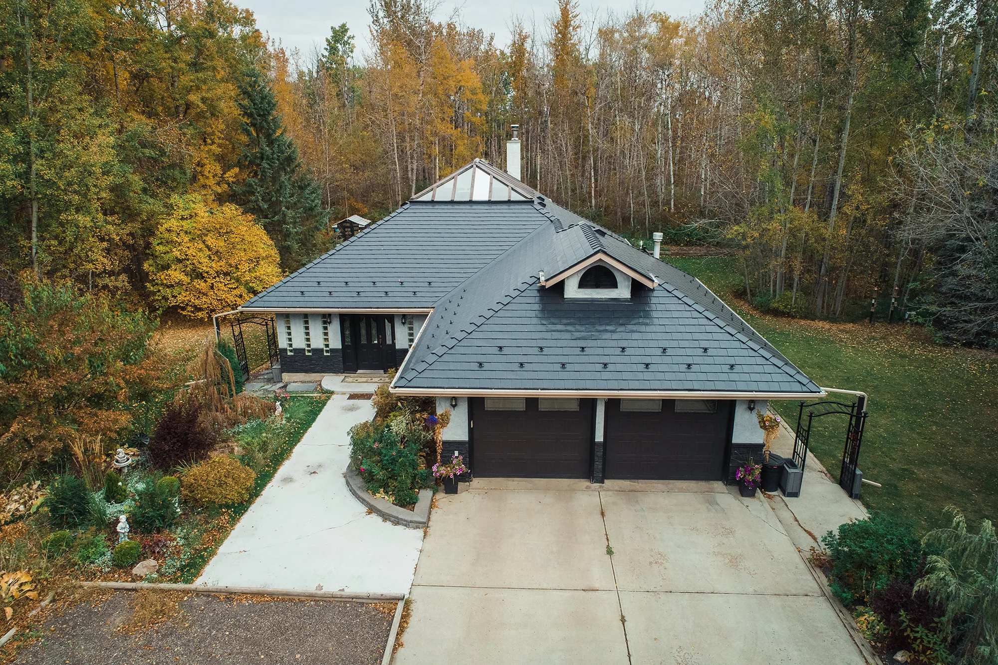 Black Interlock Slate aluminum roof on a modern home with dark roof in a forested rural area, Spruce Grove, Alberta