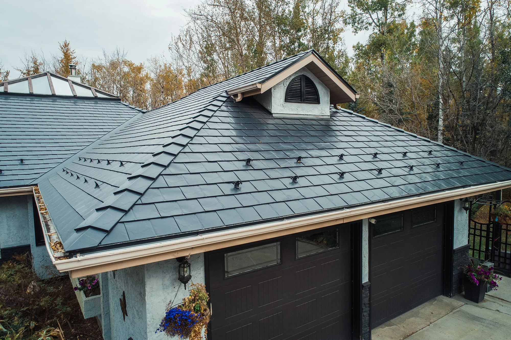 Black Interlock Slate aluminum roof on a black single-family home with dormers among tall trees, Spruce Grove, Alberta