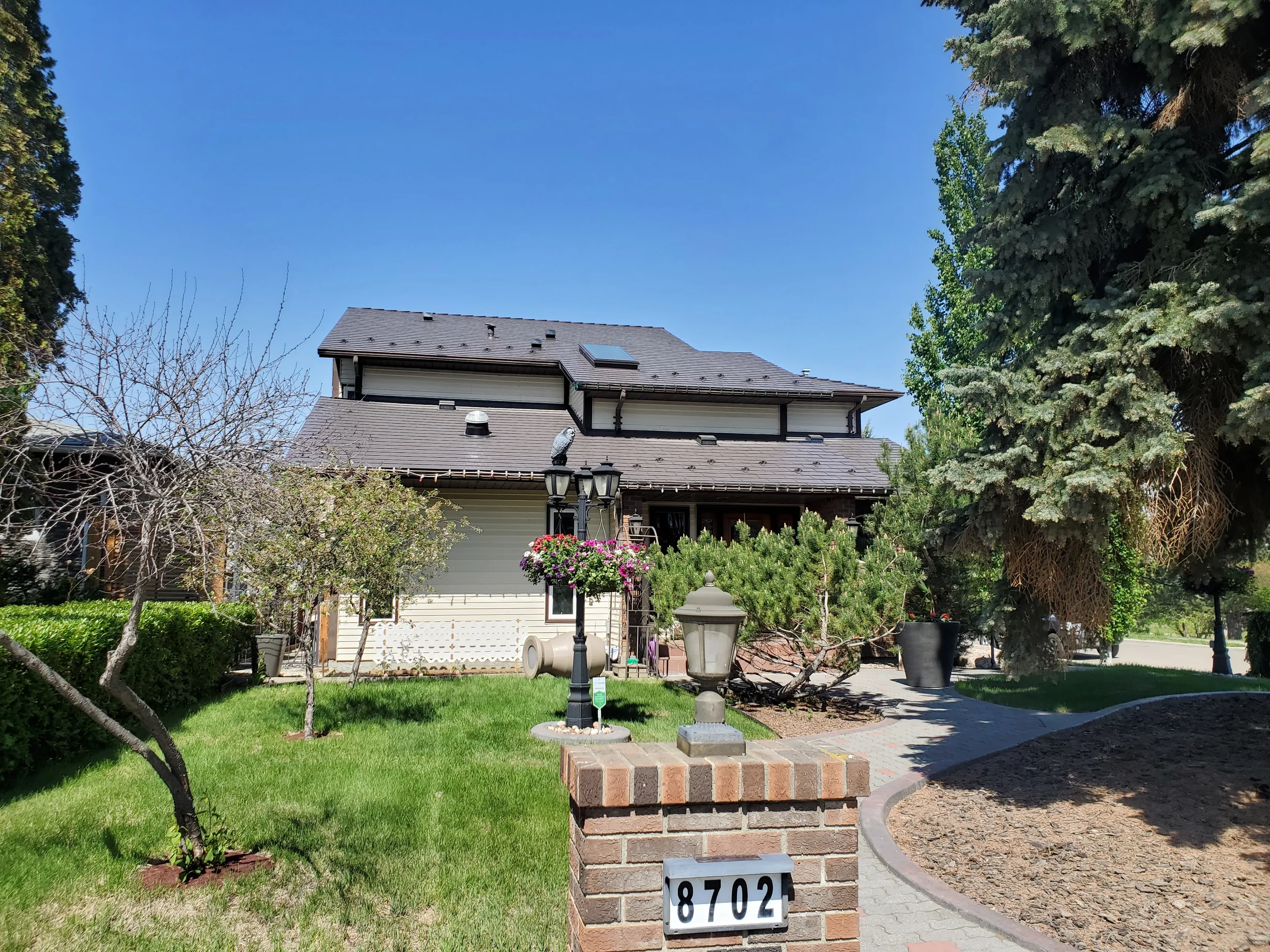 Tudor Brown Interlock Cedar Shingle aluminum roof on a Tudor style home with a brown roof among trees and a blue, Edmonton, Alberta