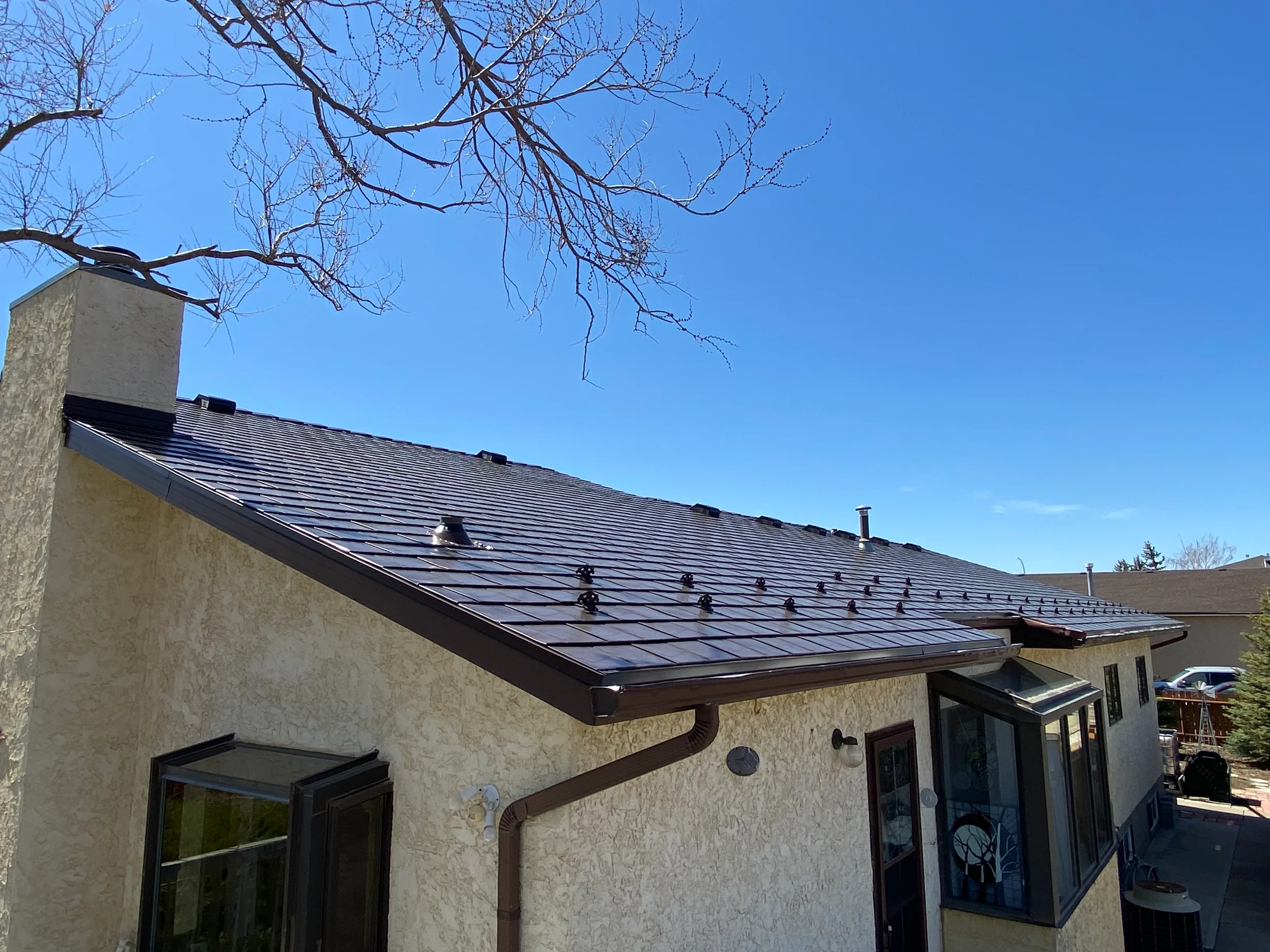 Colonial Brown Interlock Slate aluminum roof on a brown two-storey home with dormers in a rural suburban, Oyen, Alberta
