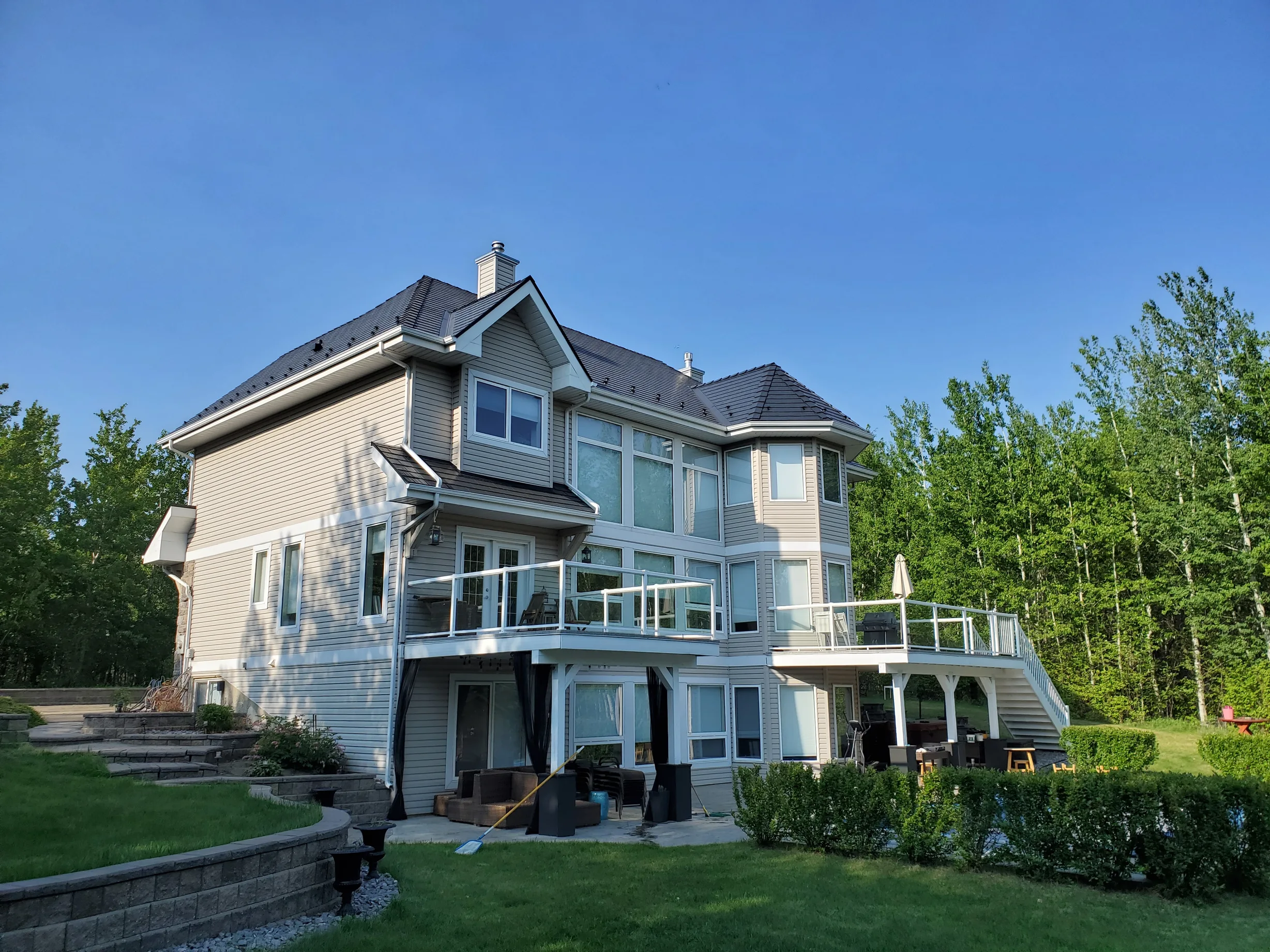 Black Interlock Cedar Shingle aluminum roof on a two-storey home with a black metal roof in a forested area, Sherwood Park, Alberta