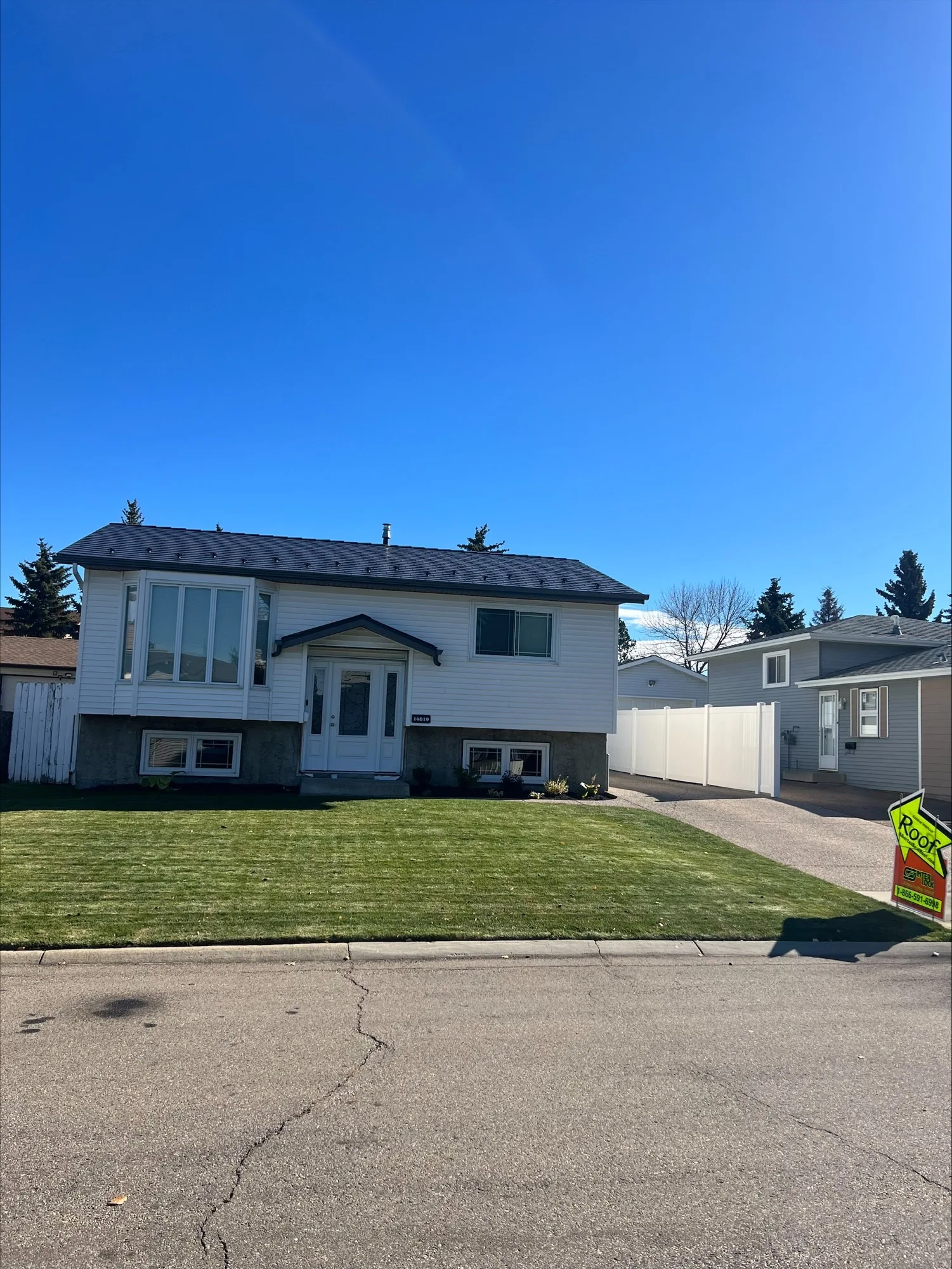 Deep Charcoal Interlock Slate aluminum roof on a white ranch-style home with a fenced yard and tall trees, Edmonton, Alberta