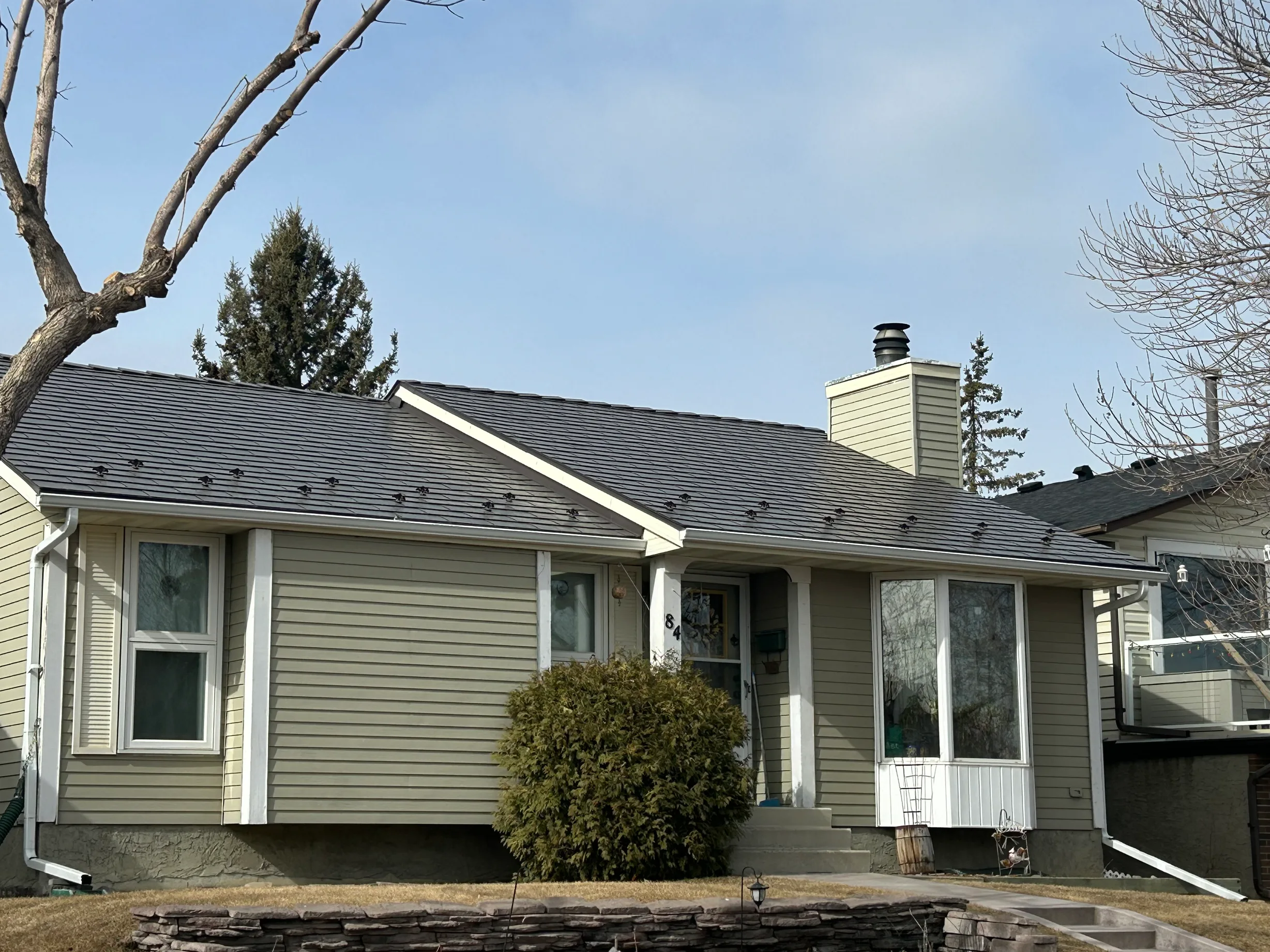 Tile Red Interlock Slate aluminum roof on a beige ranch-style home with a metal roof in a suburban, Calgary, Alberta
