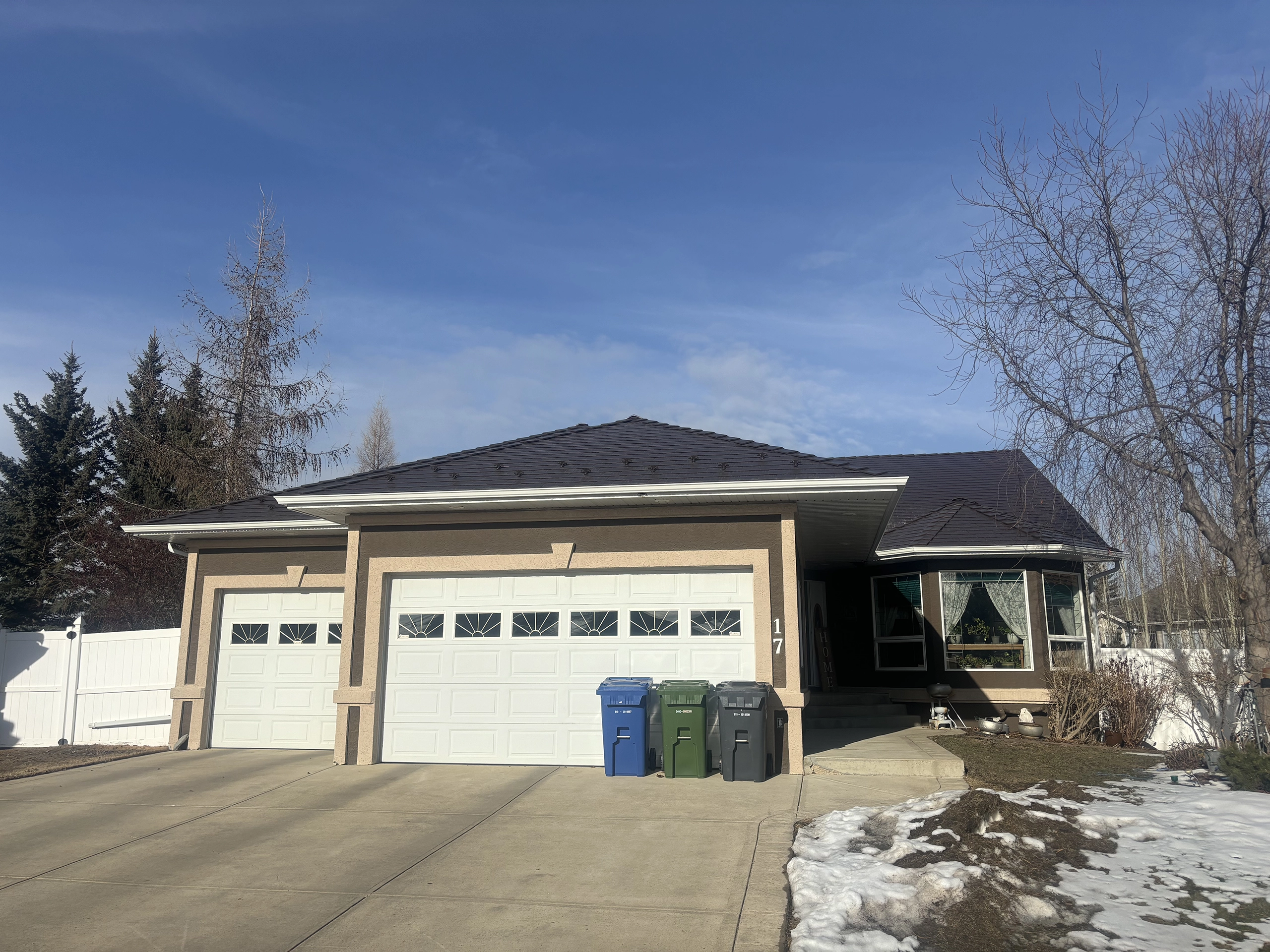 Front elevation of a single-storey ranch home in Red Deer AB featuring Interlock Colonial Brown aluminum slate metal roofing on a multi-hip complex roof.